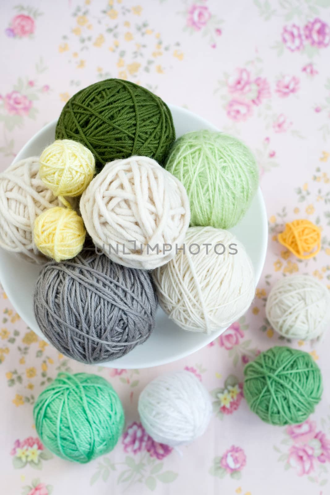 A lot of bright balls of knitting on the background of a pink flower