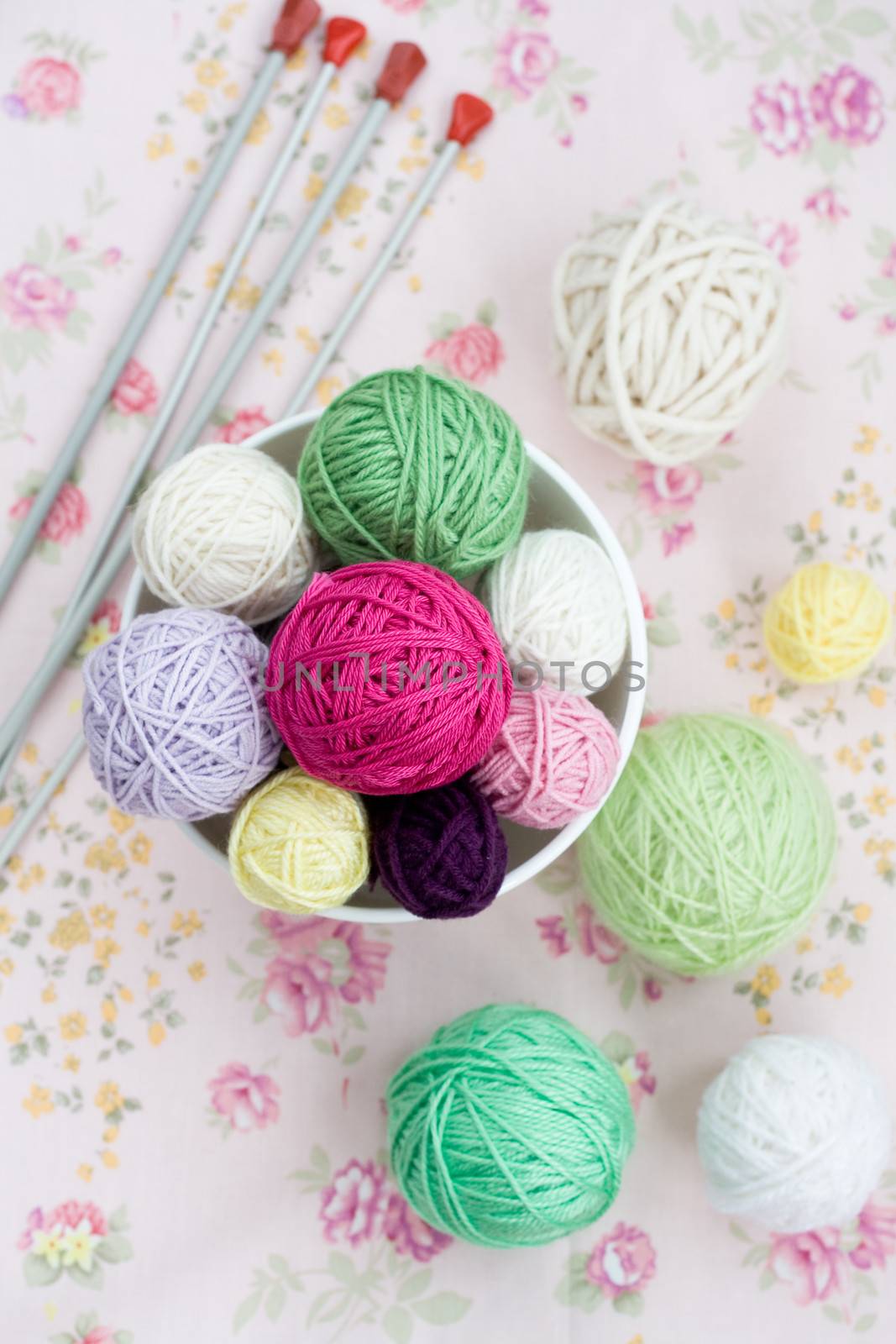 A lot of bright balls of knitting on the background of a pink flower