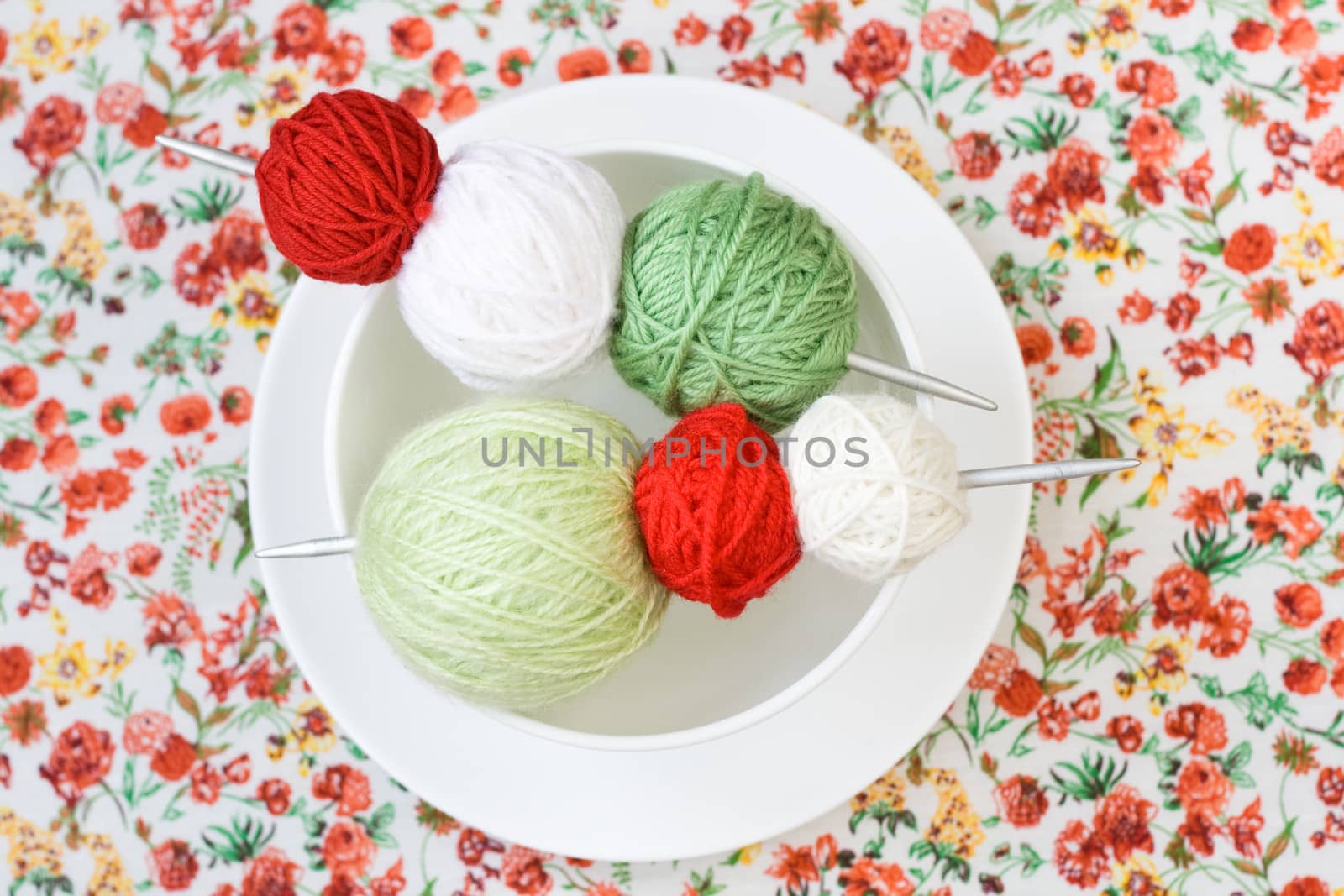 A lot of bright balls of knitting on the background of a red flower