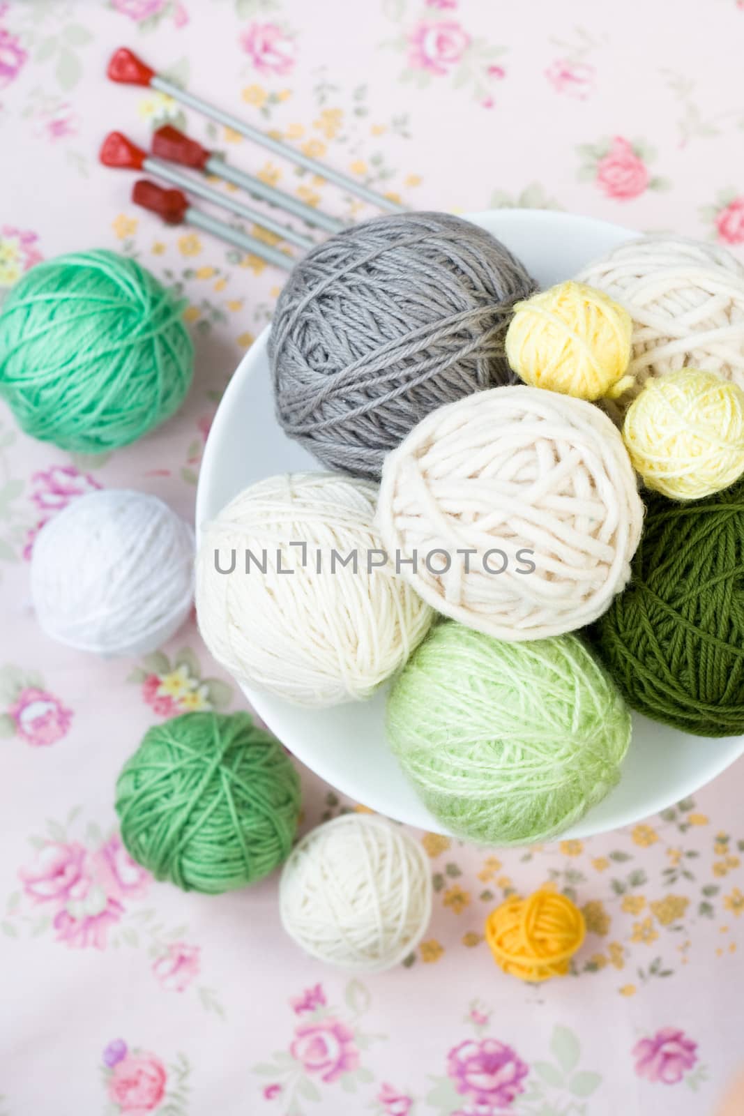 A lot of bright balls of knitting on the background of a pink flower