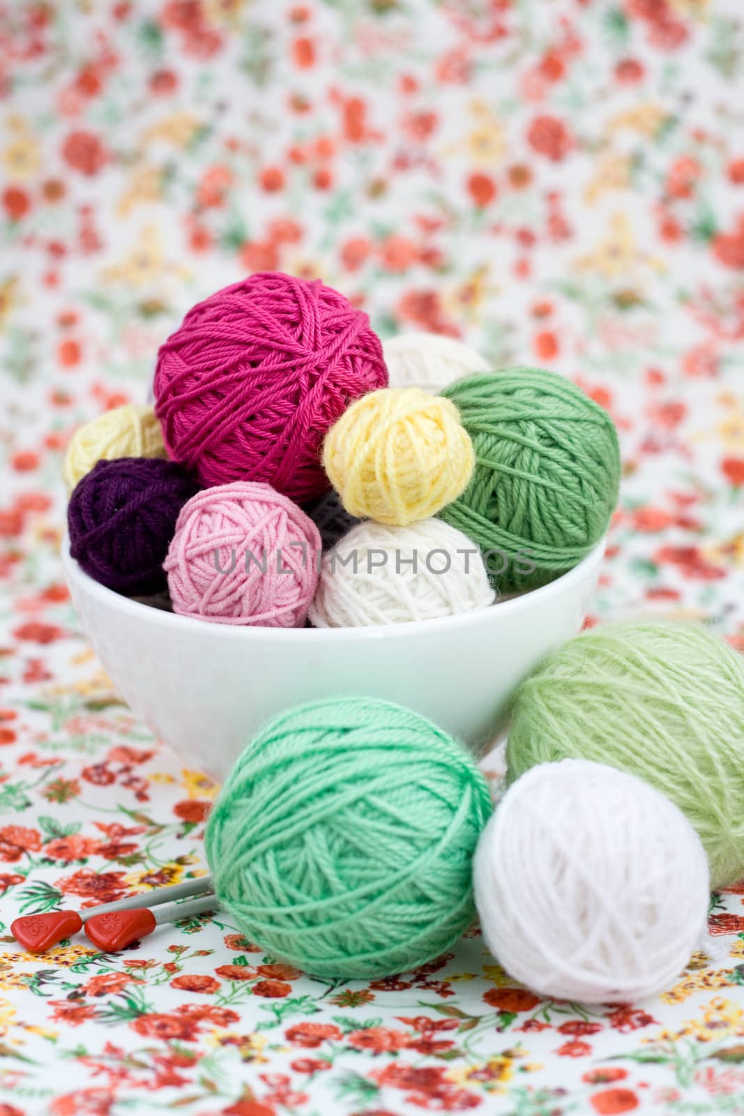 A lot of bright balls of knitting on the background of a red flower