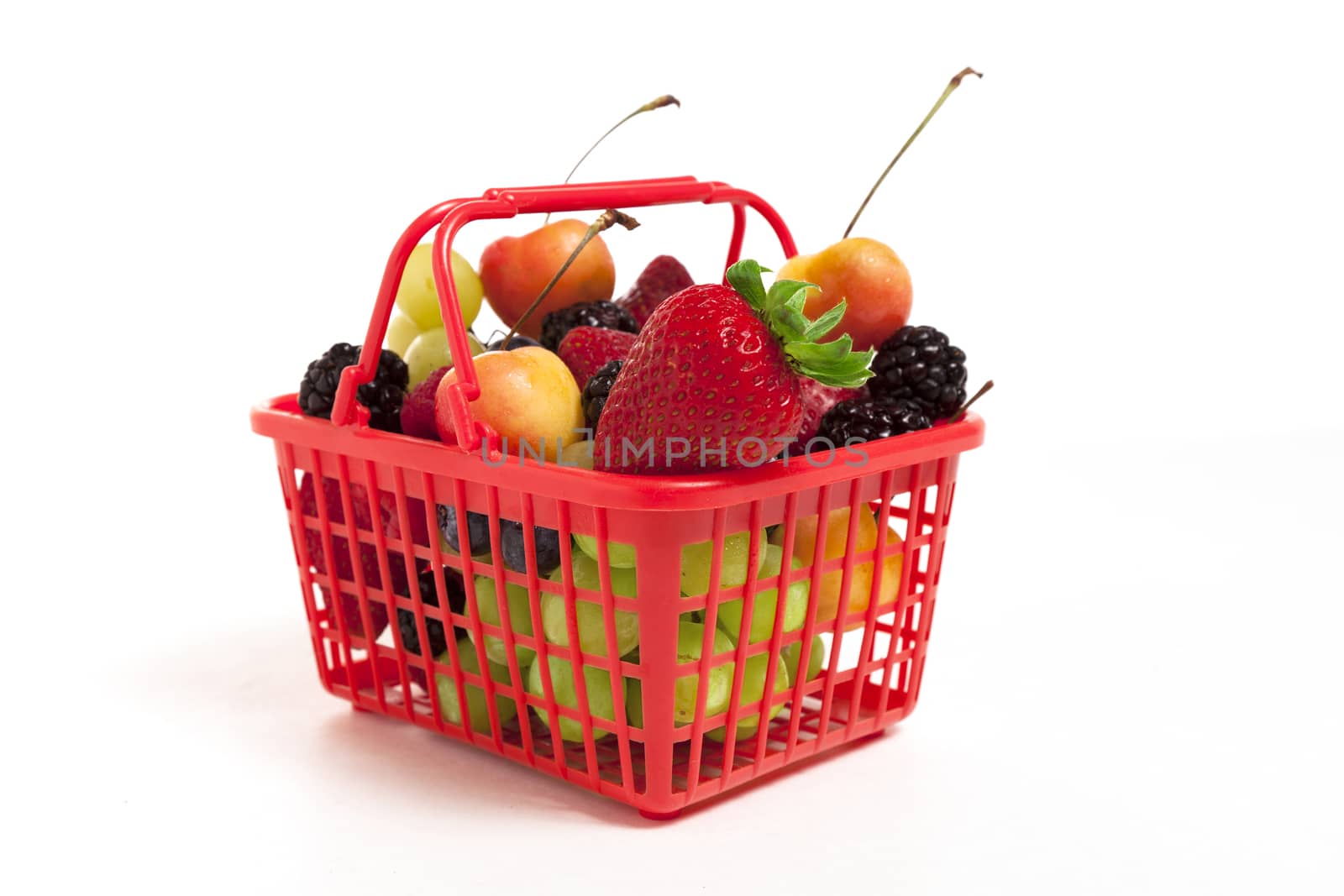 A red shopping basket full of oversized fruits and berries.