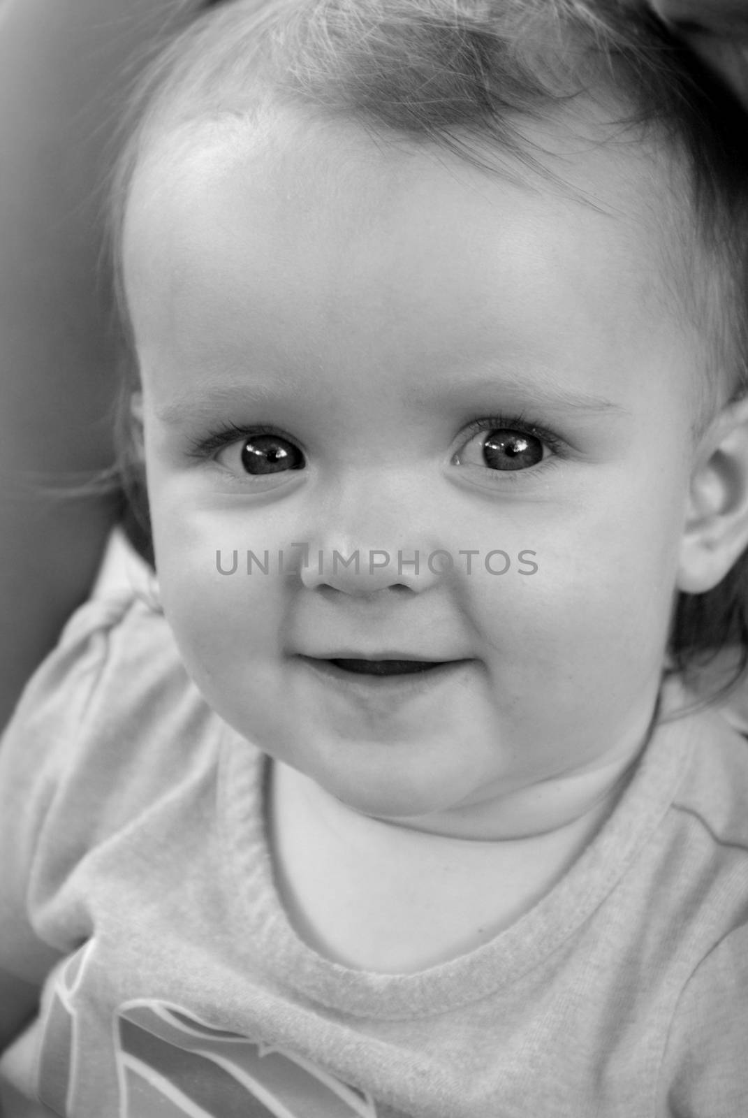 A black and white photo of a one year old baby girl sitting on her mothers lap.