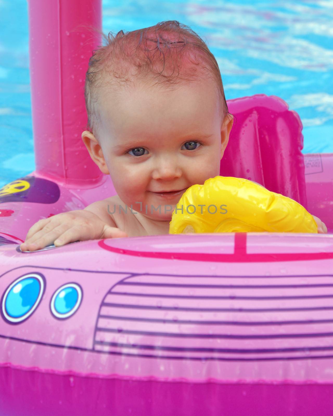 A happy one year old girl enjoys her summertime in the pool.