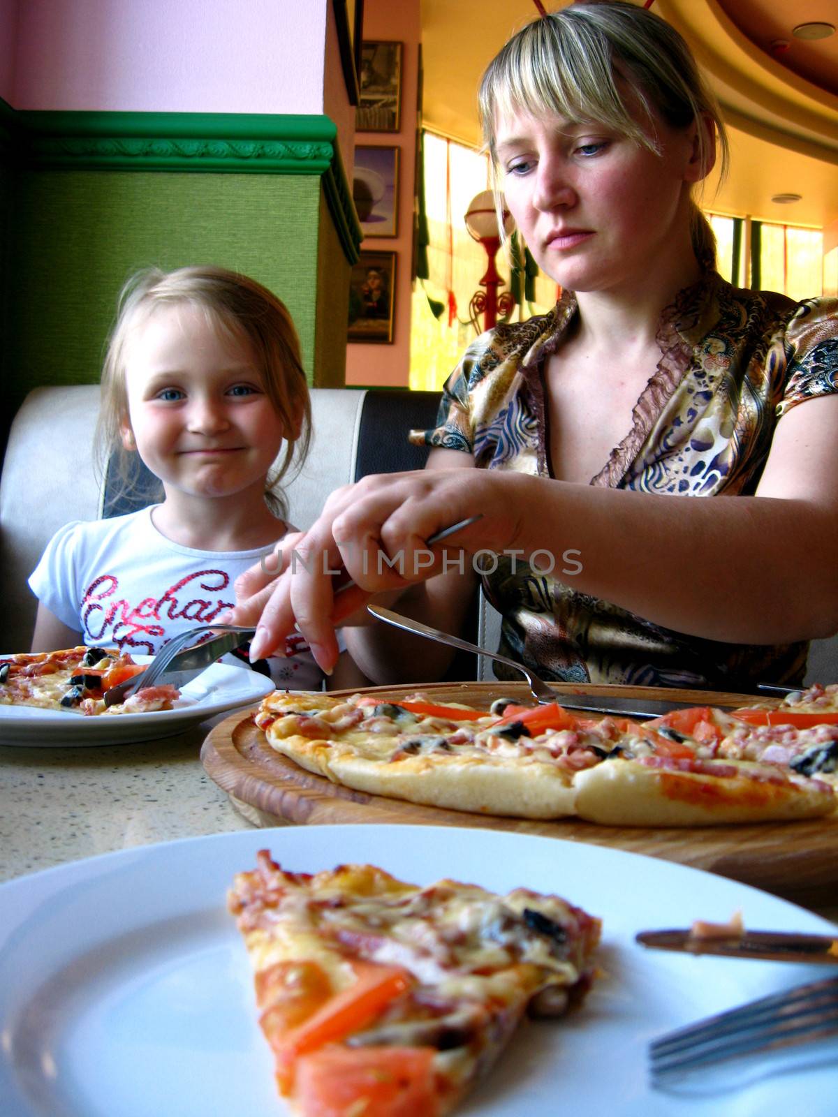 mother and daughter eating in pizzeria by alexmak