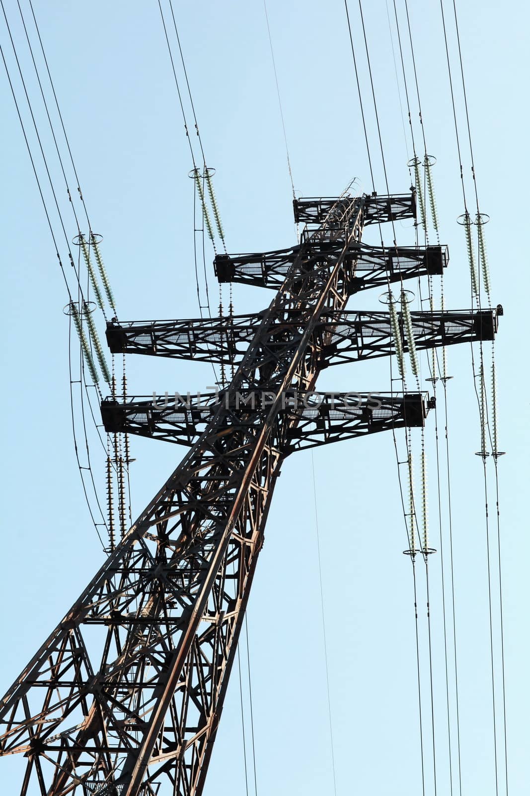 Power lines and electricity pylon  against blue sky