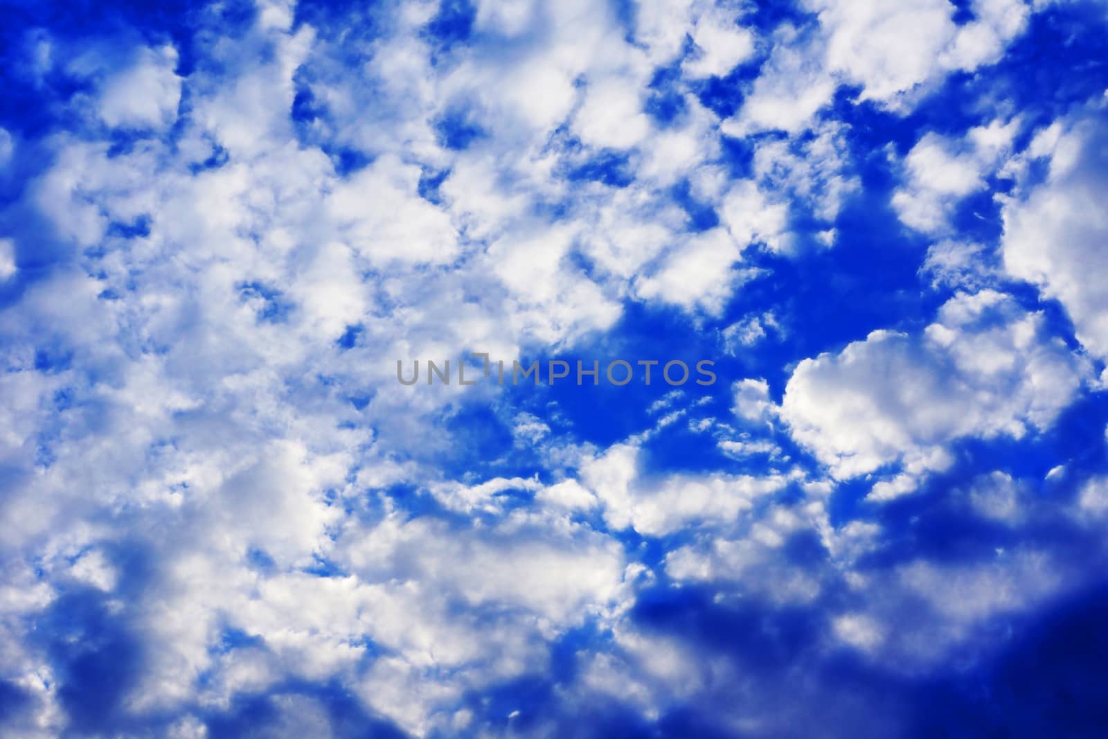 Blue sky with small puffy white clouds before sunset