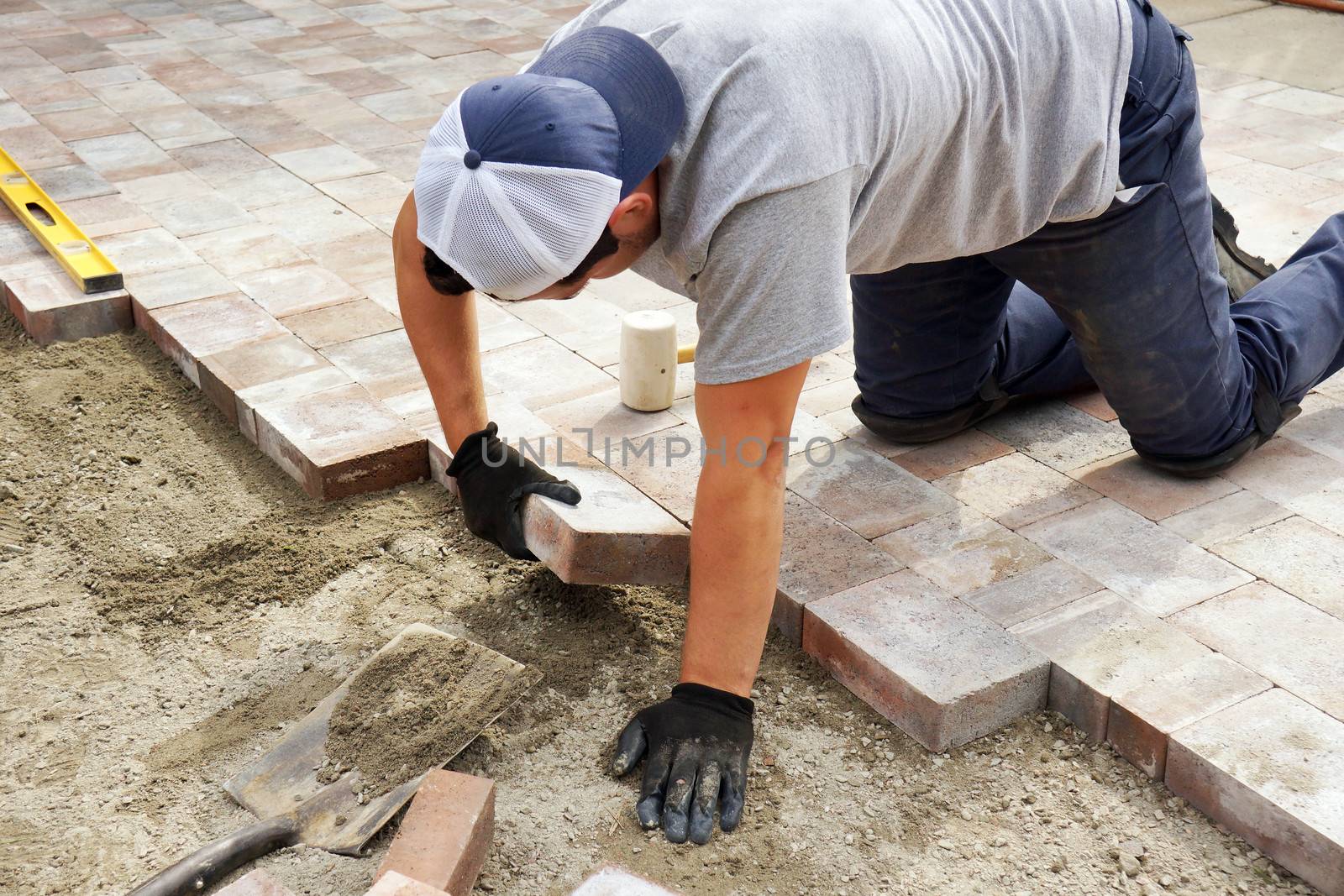 Worker installer paver bricks on large patio