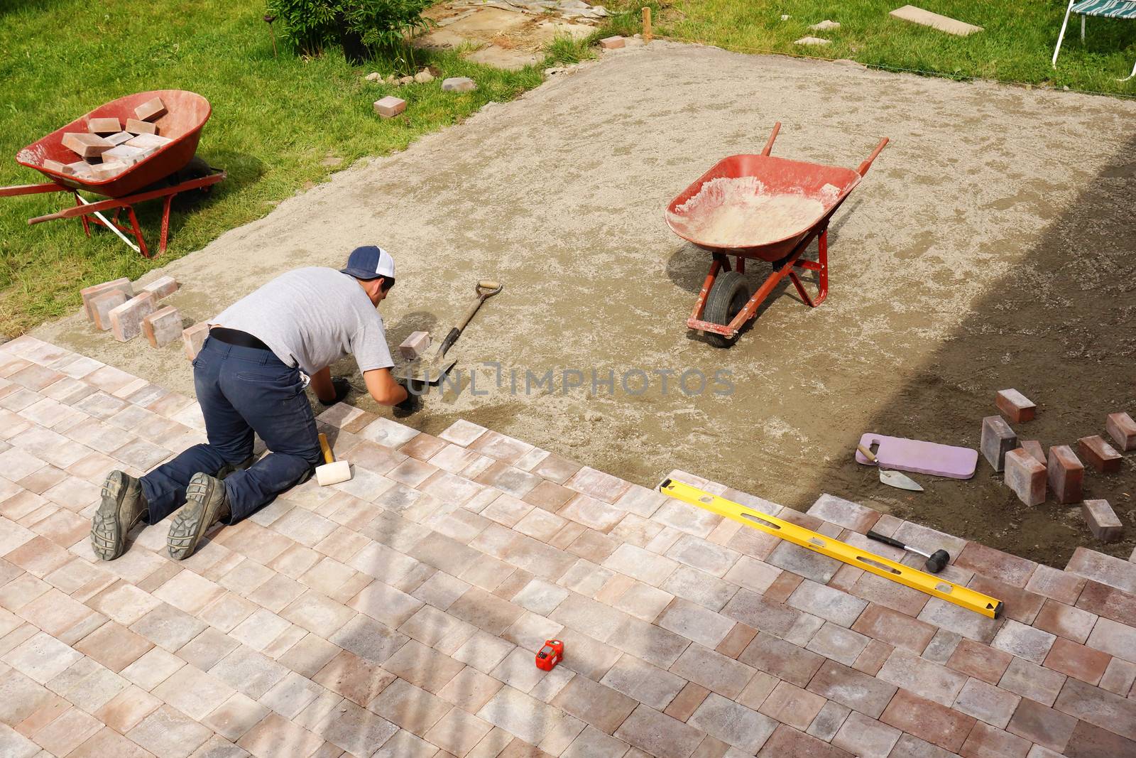 Young man installing paver bricks for large patio