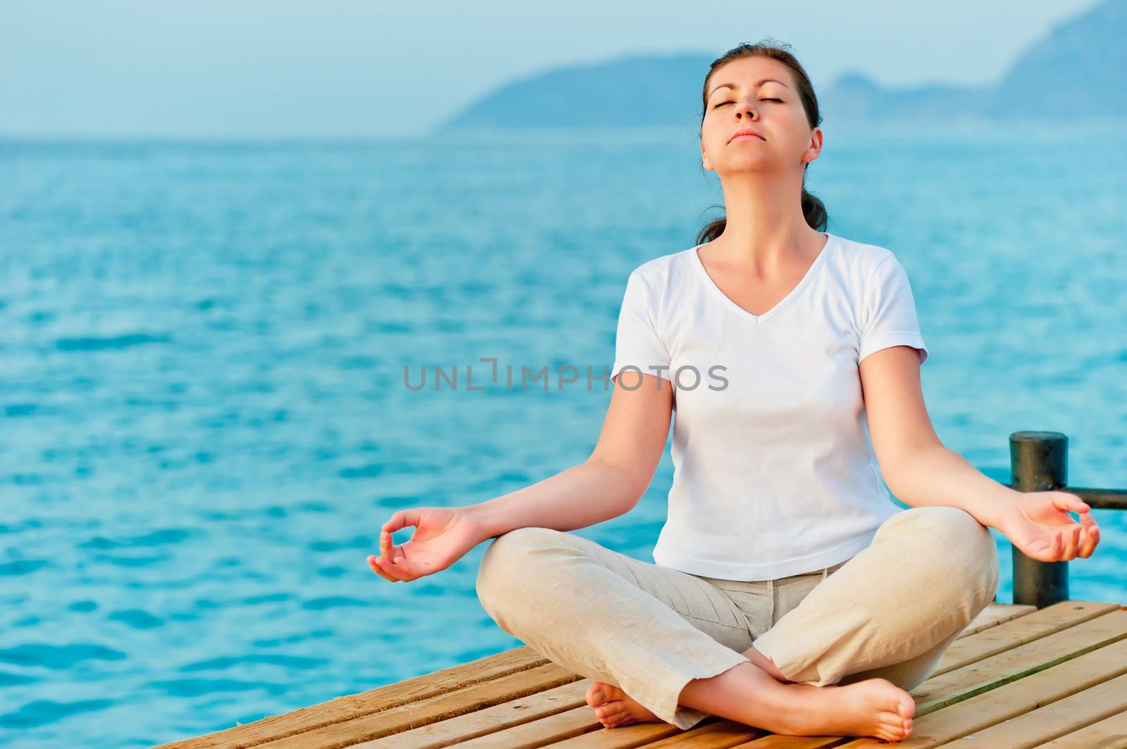 girl sitting on a pier in the lotus position by kosmsos111