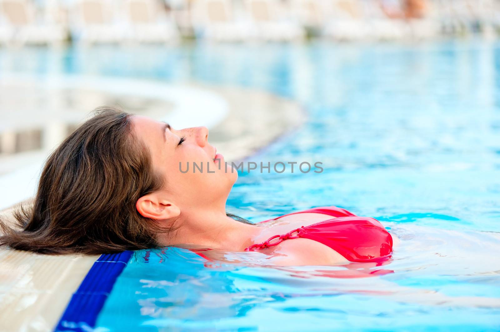 beautiful girl relaxes in the pool with your eyes closed