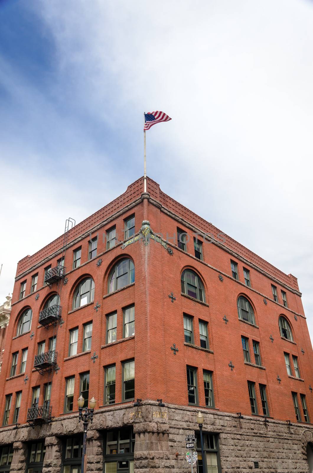 Historic red brick building in downtown Portland, Oregon with the American flag waving high above it