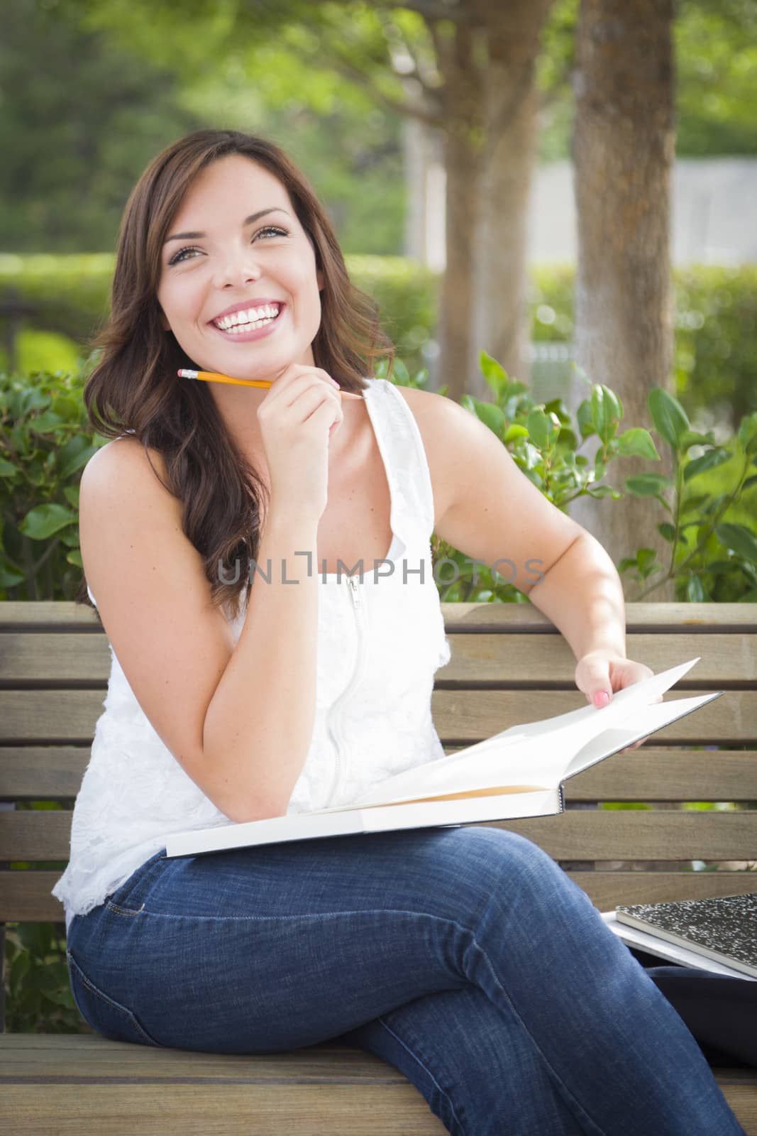 Attractive Young Adult Female Student on Bench Outdoors with Books and Pencil.