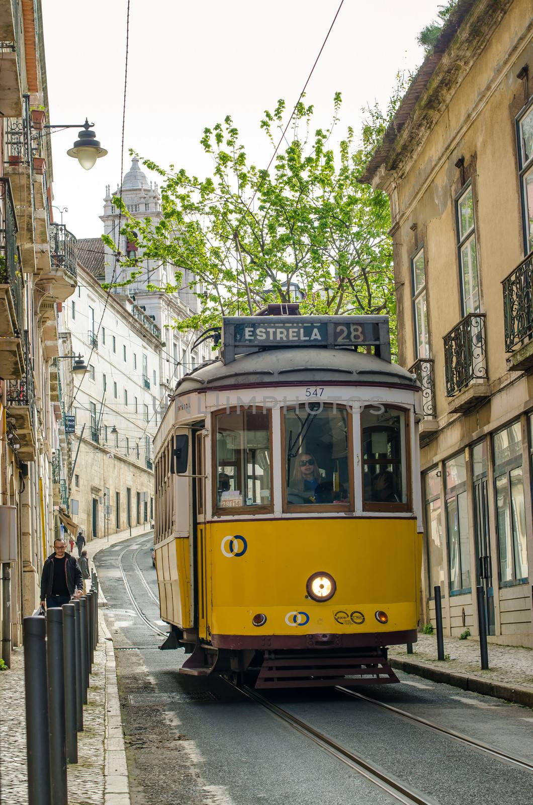 LISBON, PORTUGAL - APRIL 8: A traditional tram is making its way through a narrow street in Lisbon, Portugal on April 8, 2013. The five urban tramway lines mainly serve as a tourist attraction.