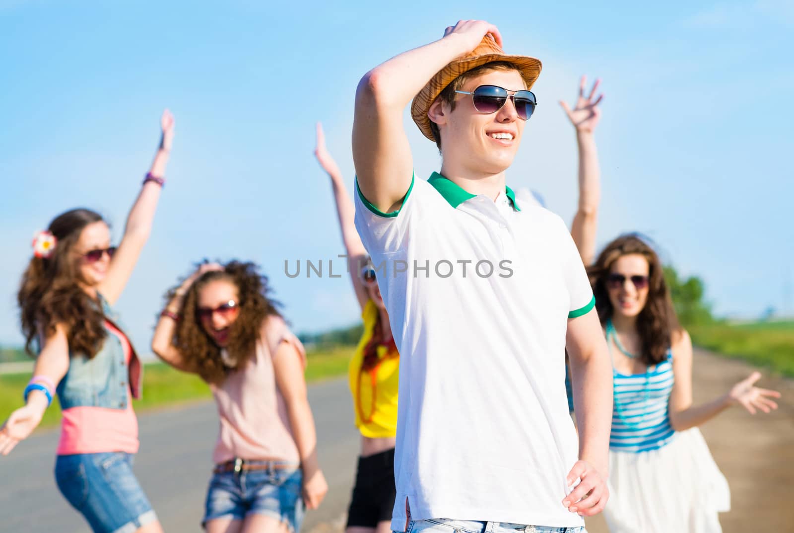 young man in sunglasses, a hat holds a hand on a background of blue sky and friends