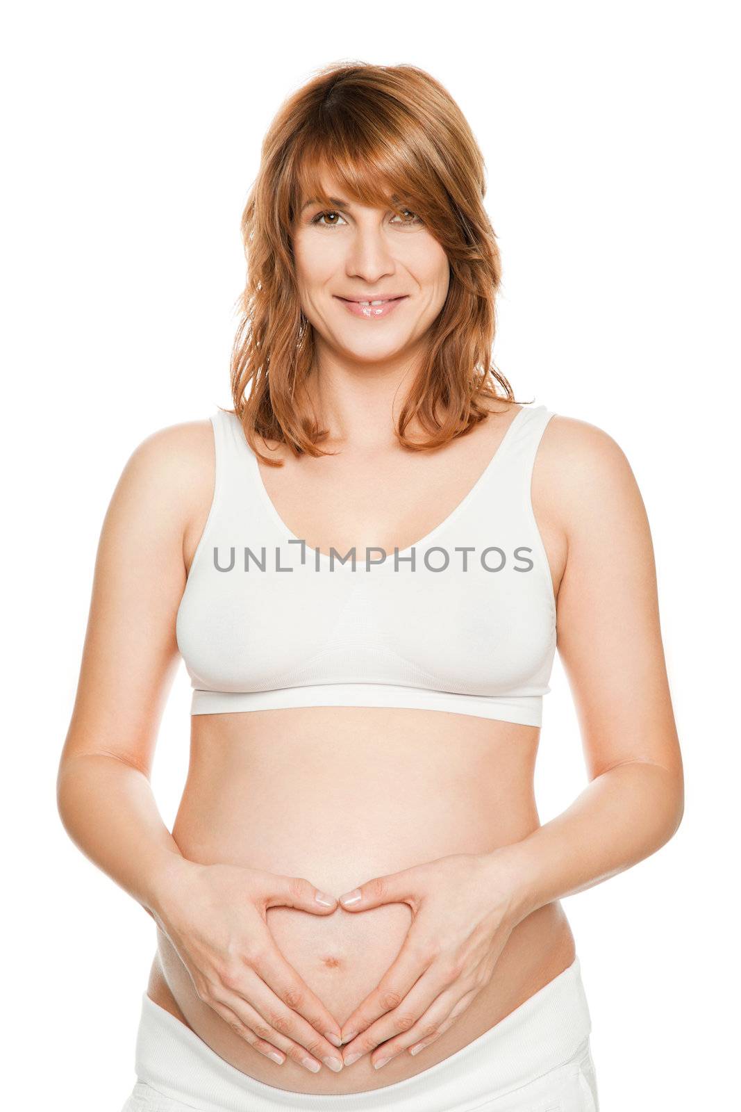 Smiling pregnat woman holding hands in heart sign on tummy