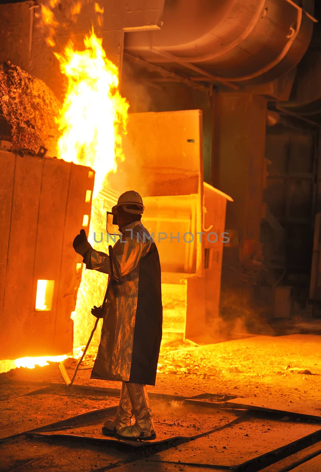 A steel worker takes a sample from oven