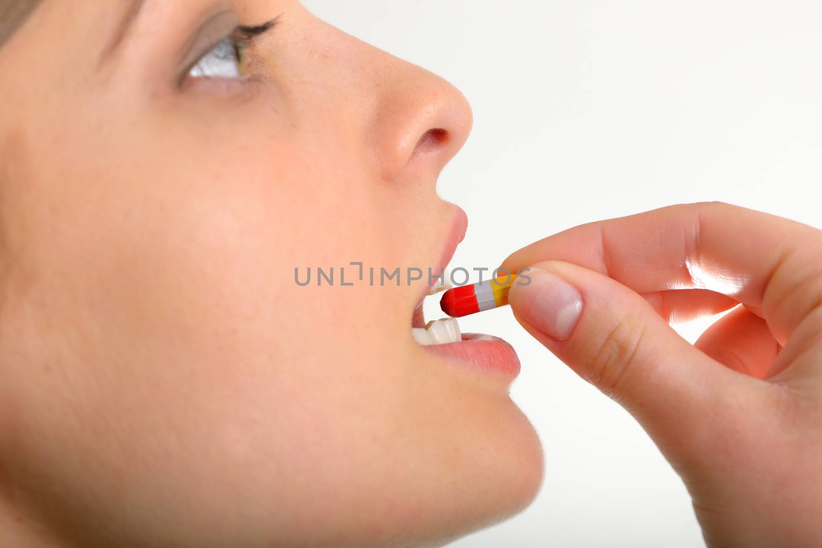close-up young woman on studio isolated white background taking pill
