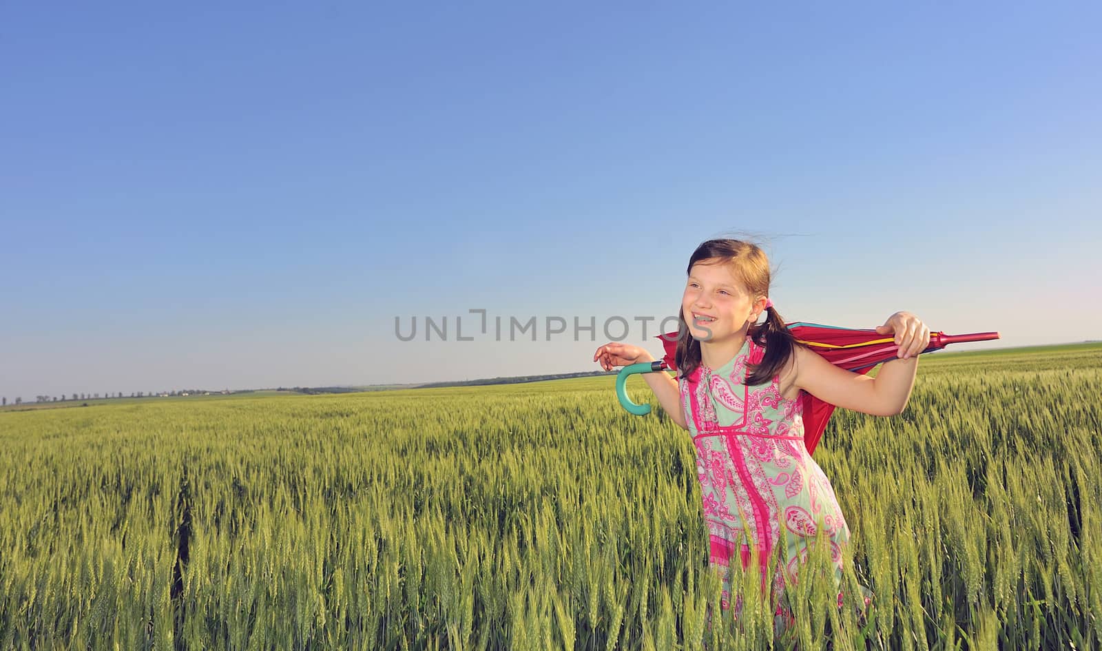 a little girl with a umbrella in green field