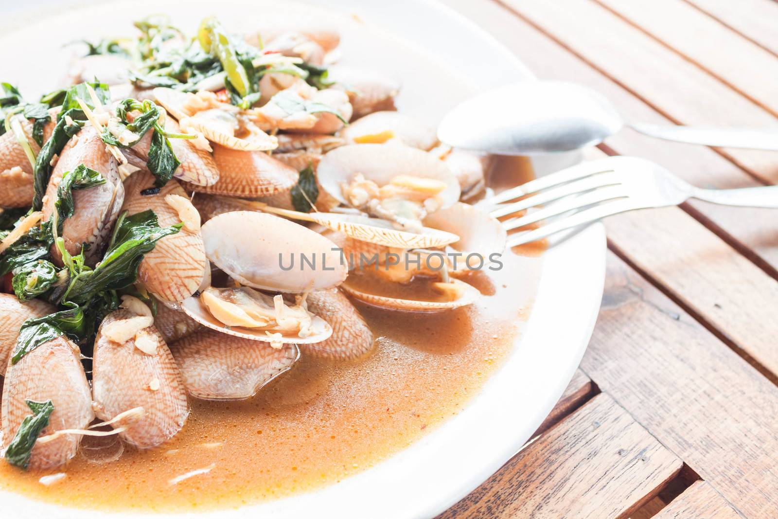 Stir fried clams with roasted chili paste on wooden table by punsayaporn