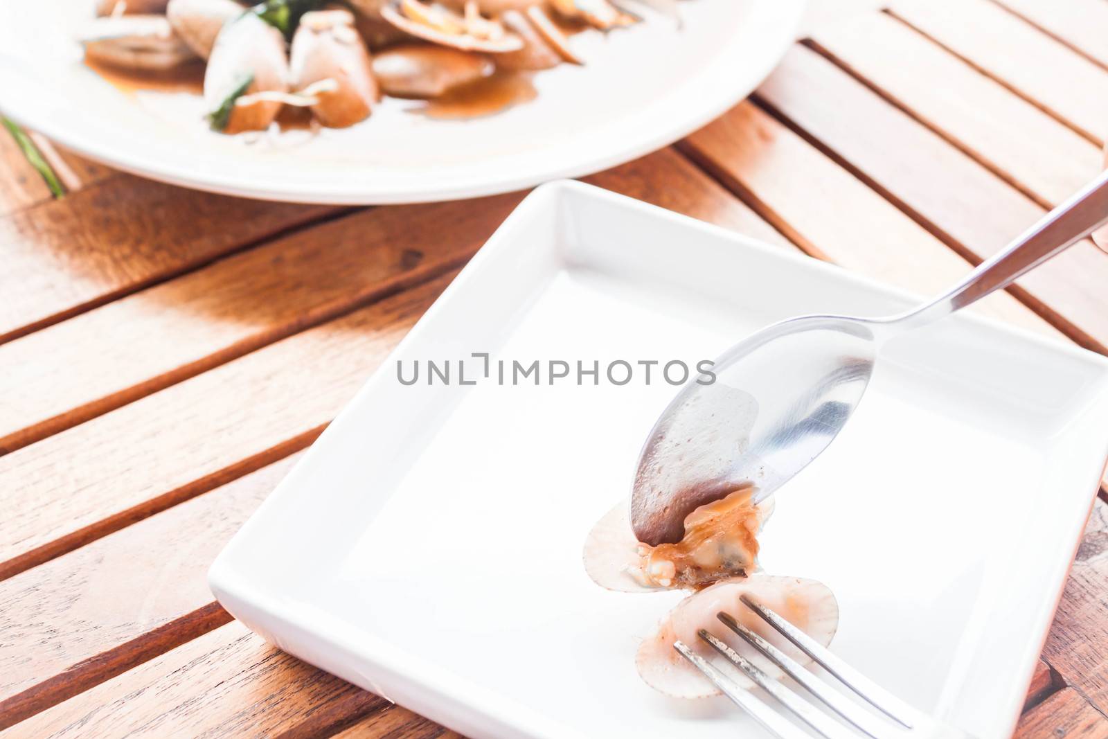 Spoon and fork on stir fried clams with roasted chili paste