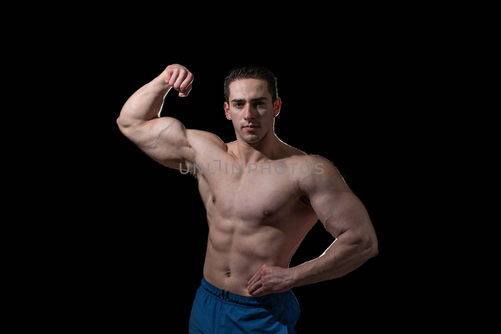 bodybuilder showing his biceps on black background by JalePhoto