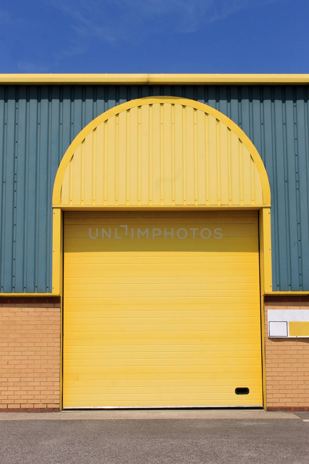 Exterior of modern warehouse building with arched yellow door.