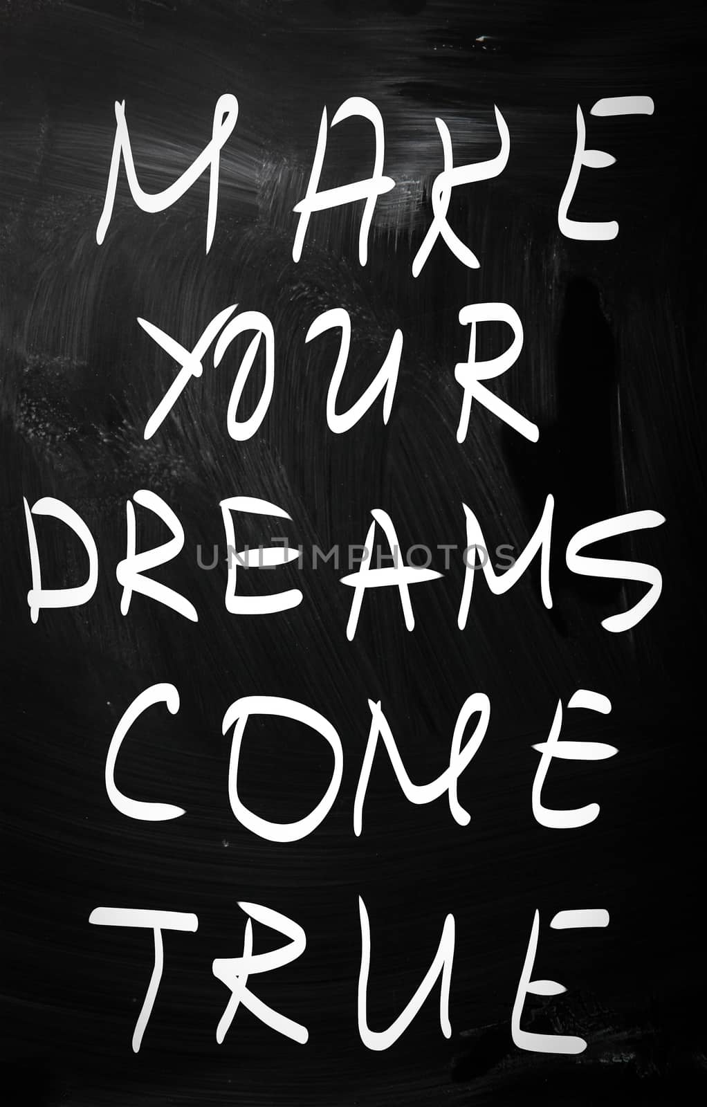 "Make your dreams come true" handwritten with white chalk on a blackboard