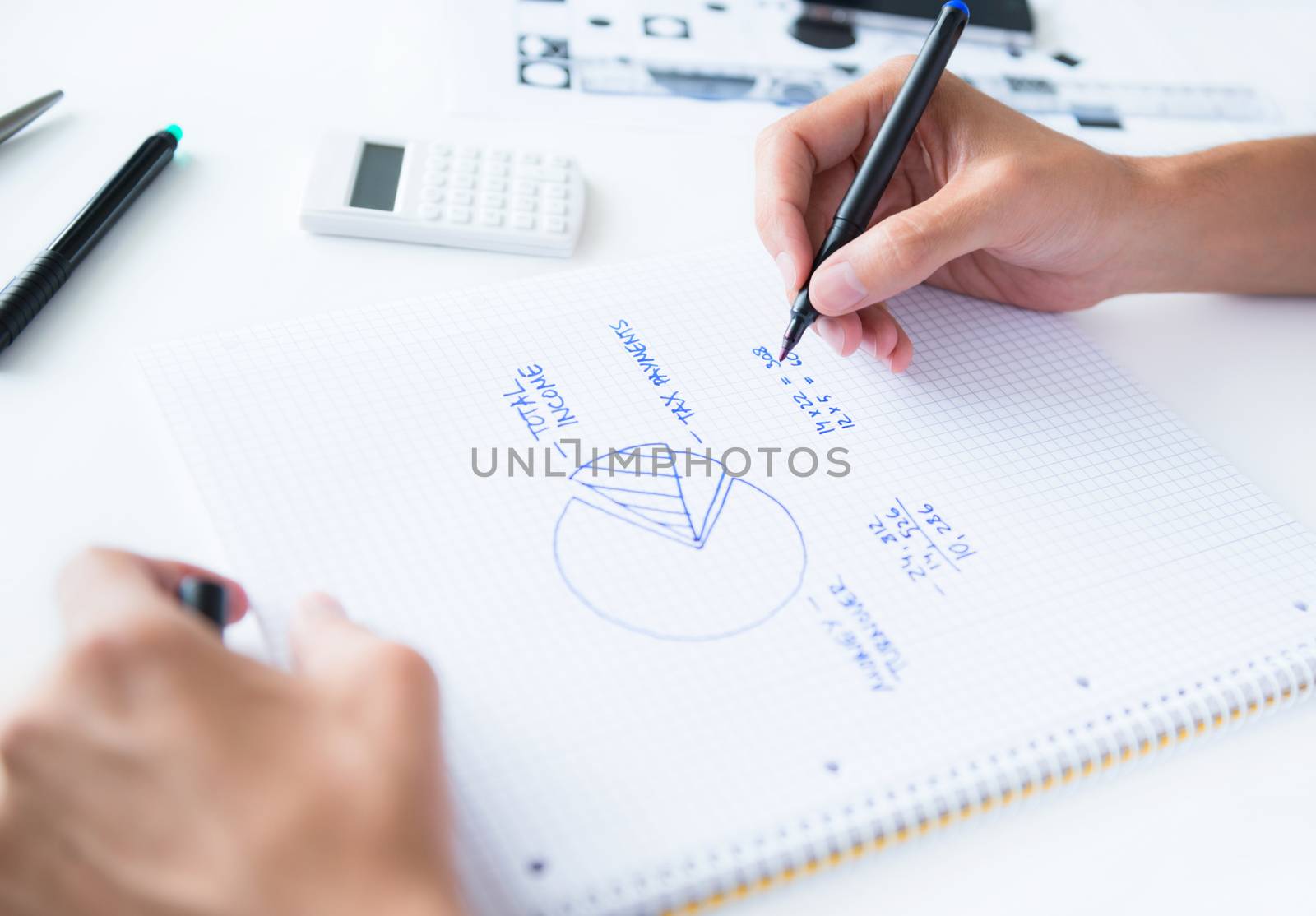 Person sitting at the desk, calculating home earnings and drawing circular diagram with numbers