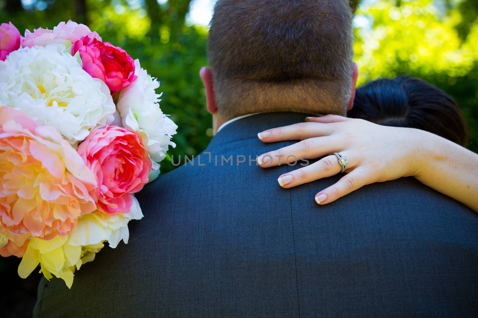 The bride puts her hand over the shoulder of the groom while dancing to create this image that focuses on her wedding band ring.