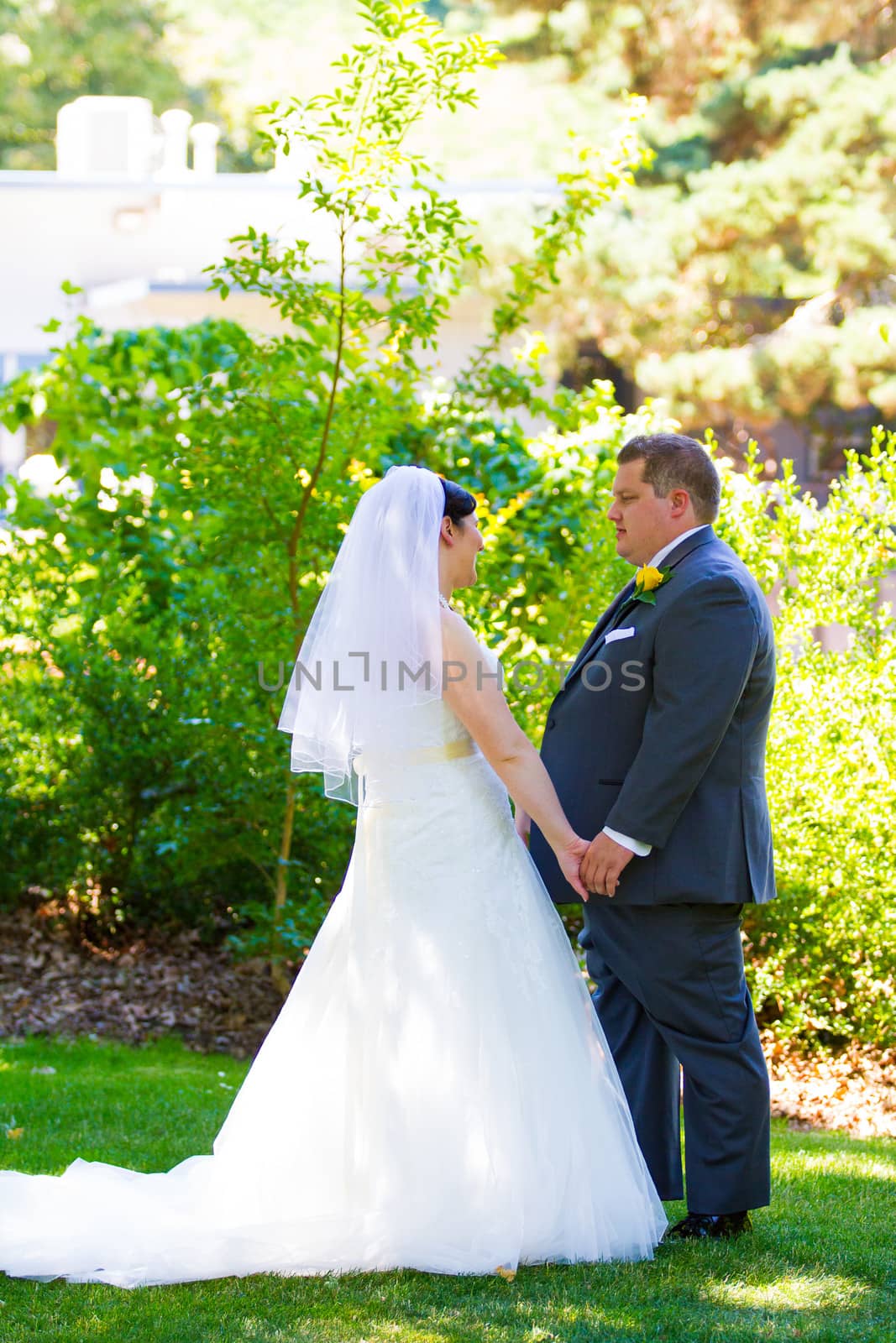 A portrait of a wedding couple with the bride and groom on their wedding day at a park outdoors.