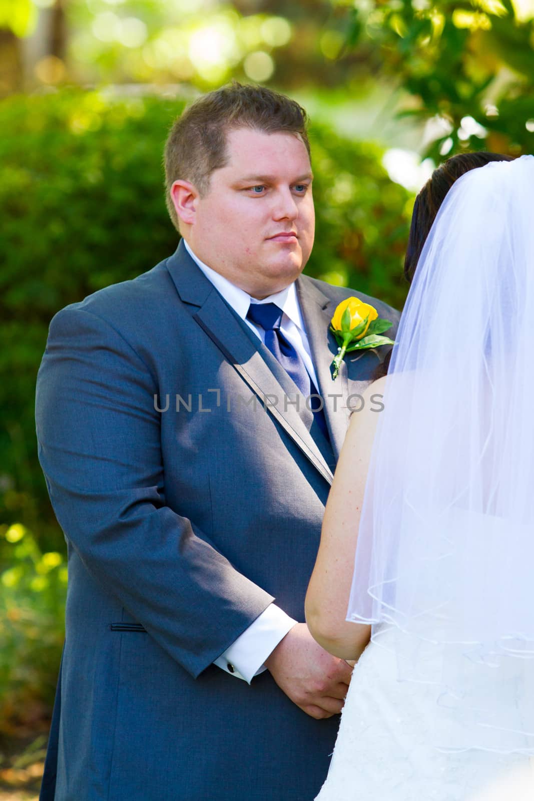Vertical portrait of a groom during his vows at a ceremony on his wedding day.
