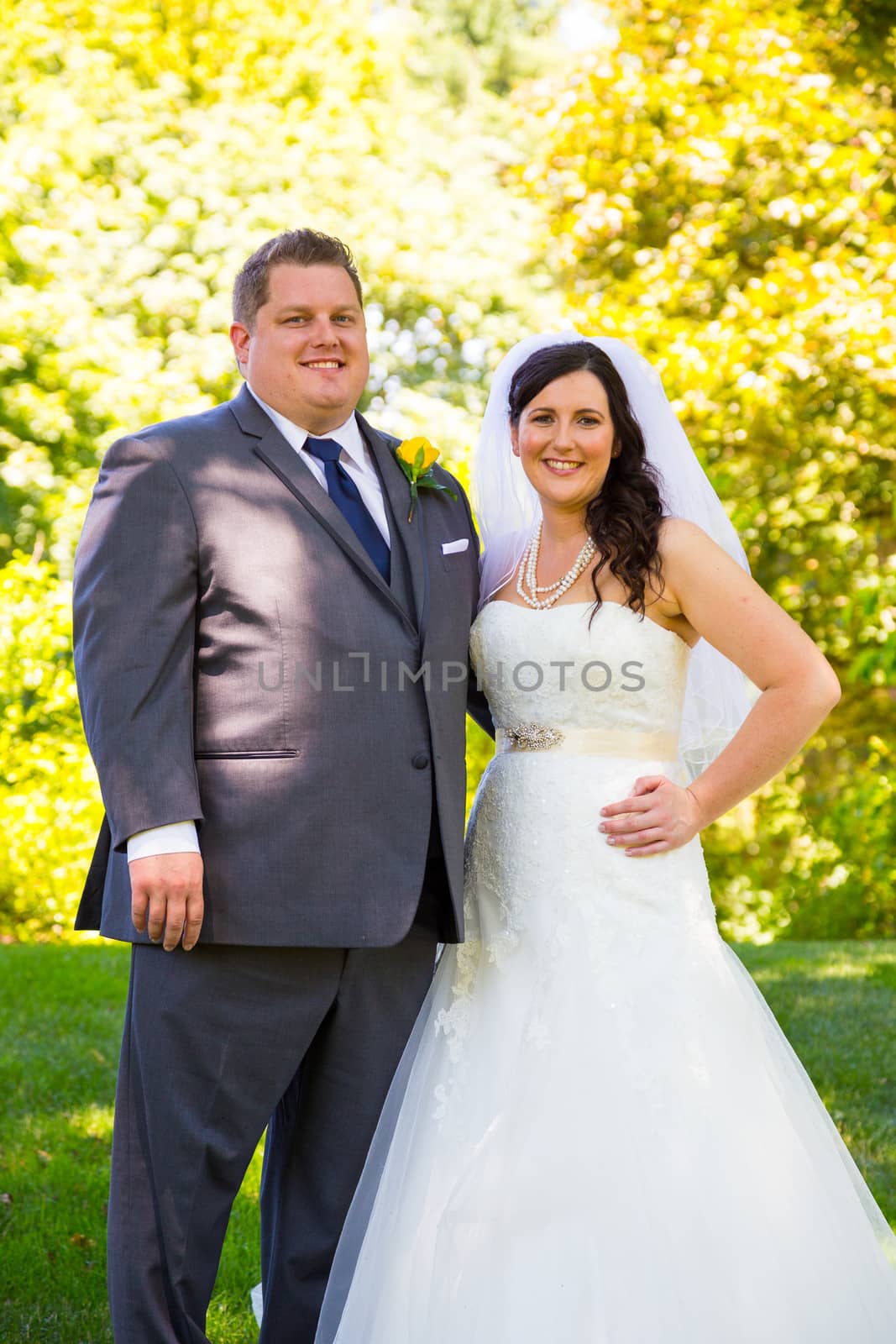 A beautiful bride and groom pose for portraits on their wedding day at a park outdoors.