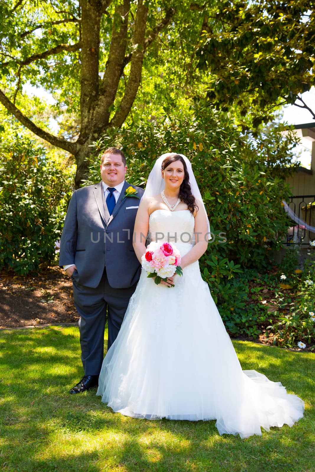 A beautiful bride and groom pose for portraits on their wedding day at a park outdoors.