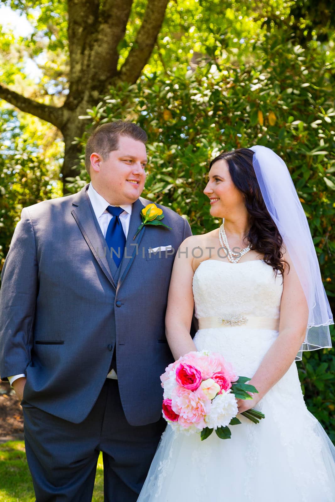 A beautiful bride and groom pose for portraits on their wedding day at a park outdoors.