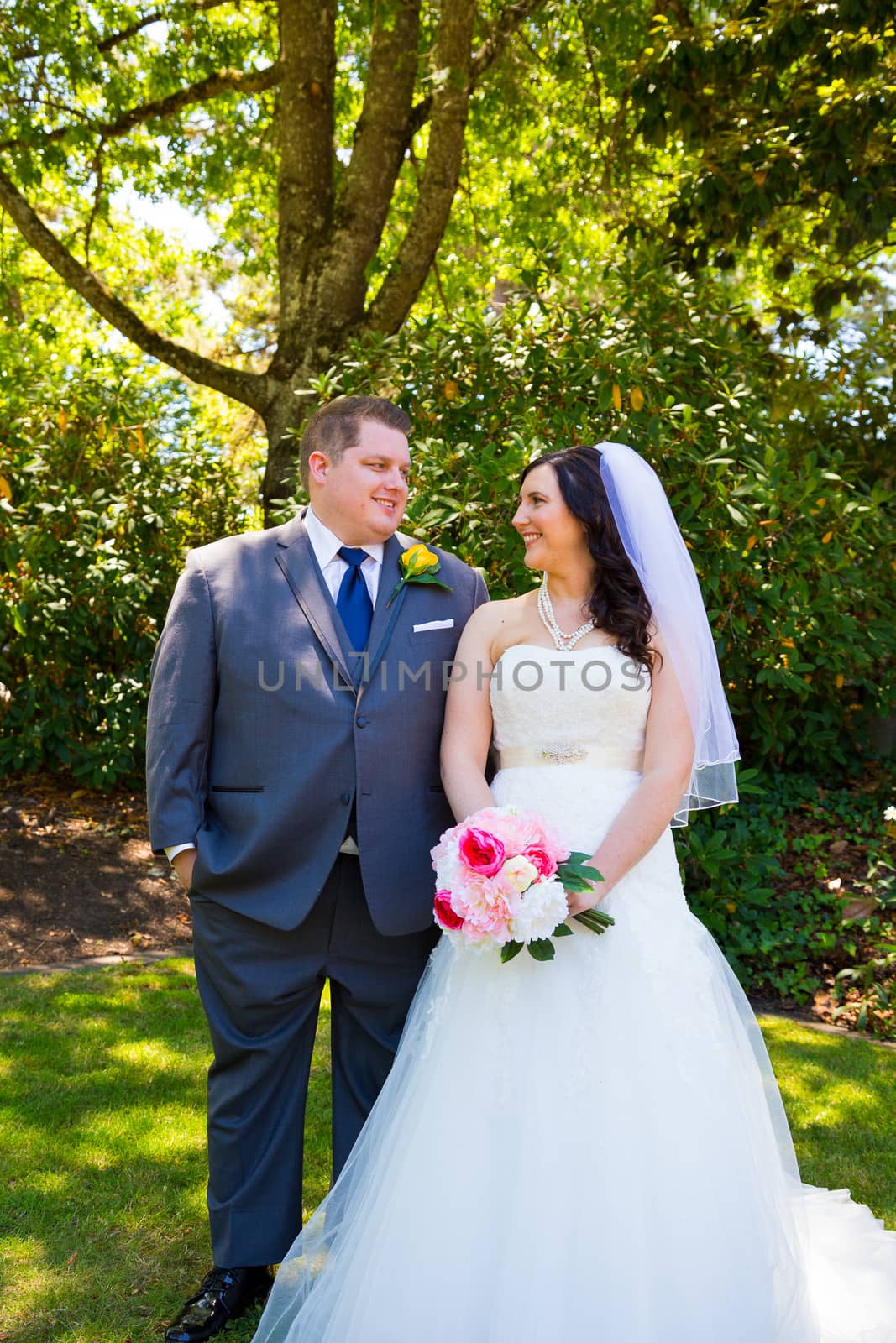 A beautiful bride and groom pose for portraits on their wedding day at a park outdoors.