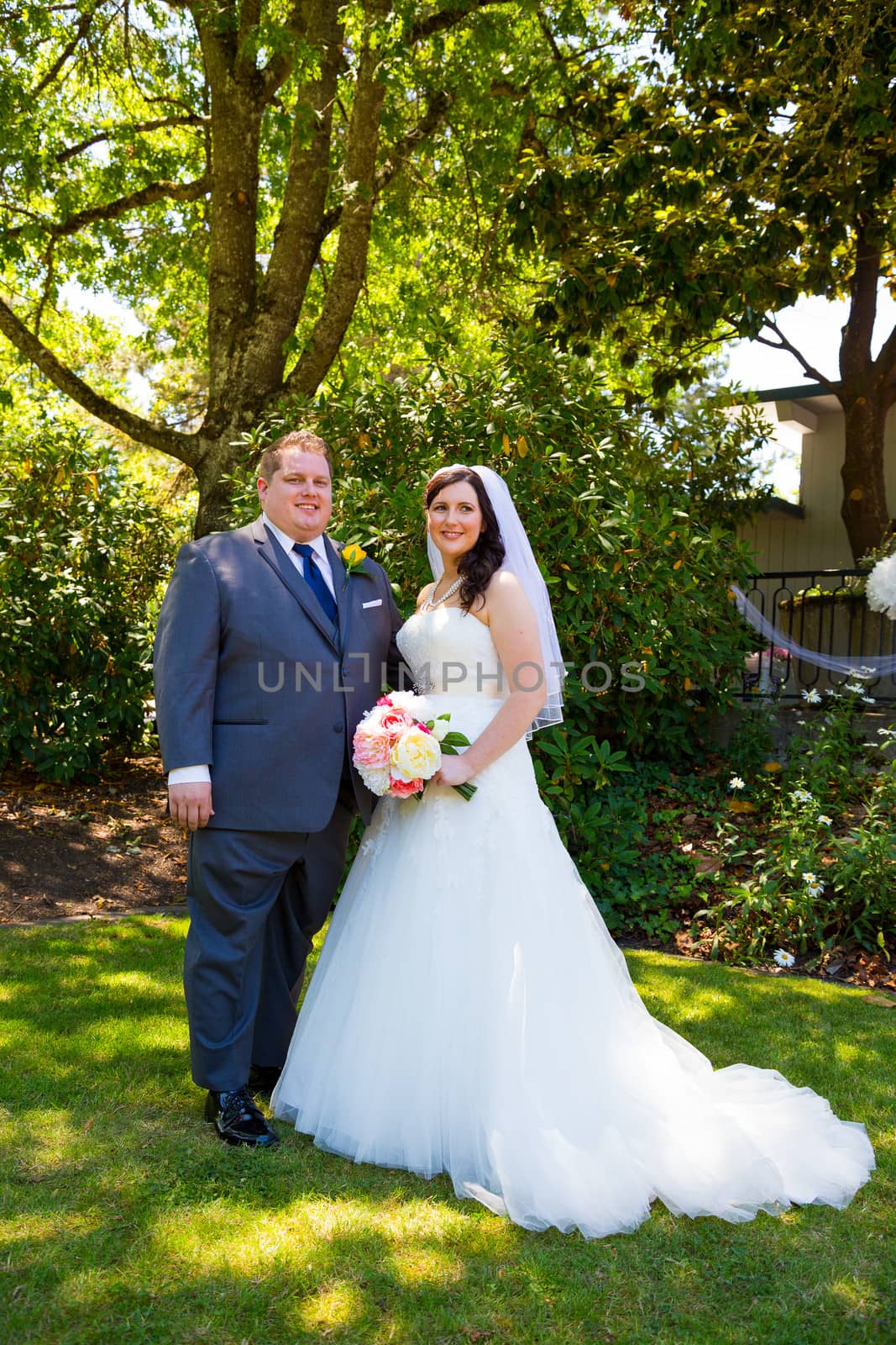 A beautiful bride and groom pose for portraits on their wedding day at a park outdoors.