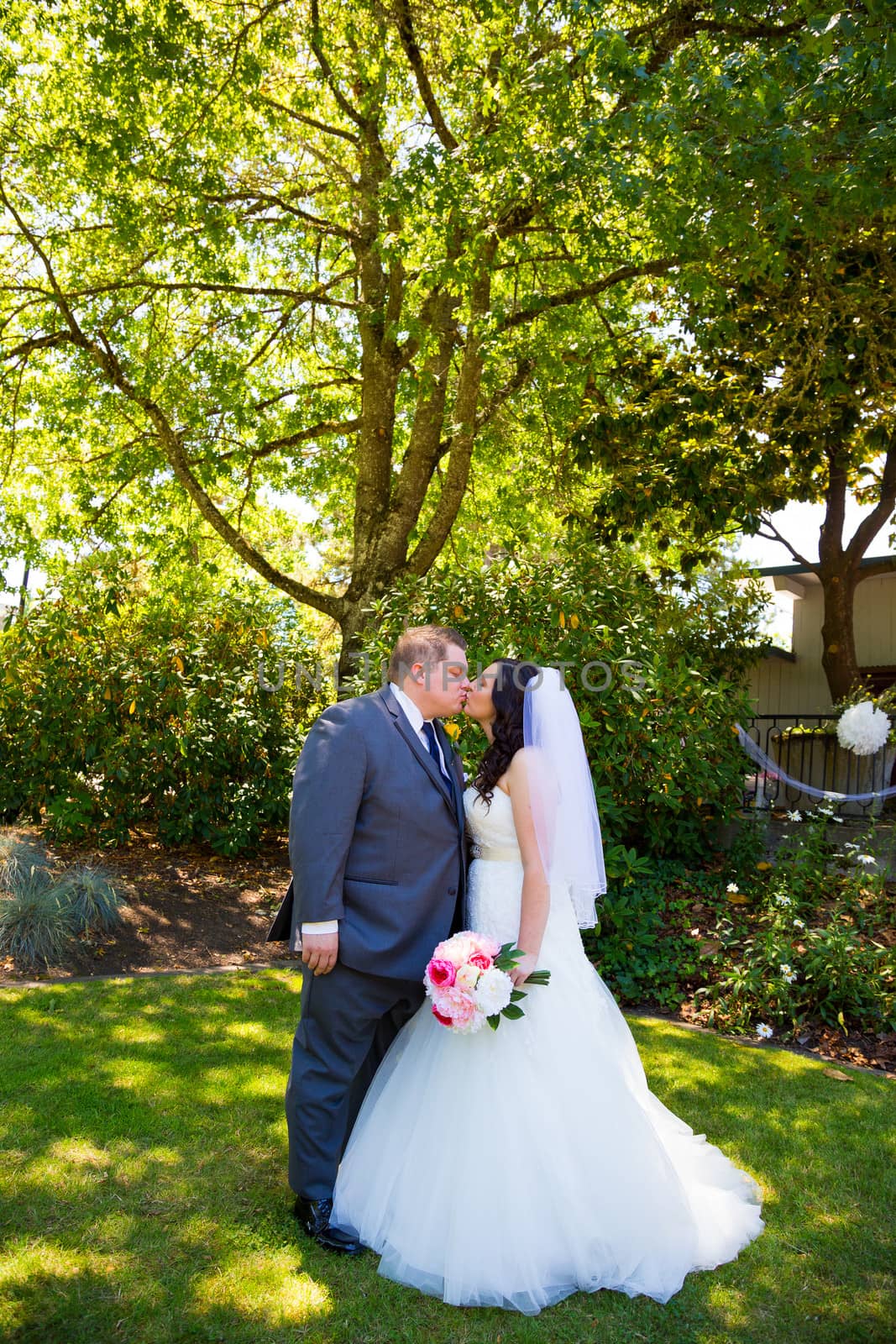 A beautiful bride and groom pose for portraits on their wedding day at a park outdoors.