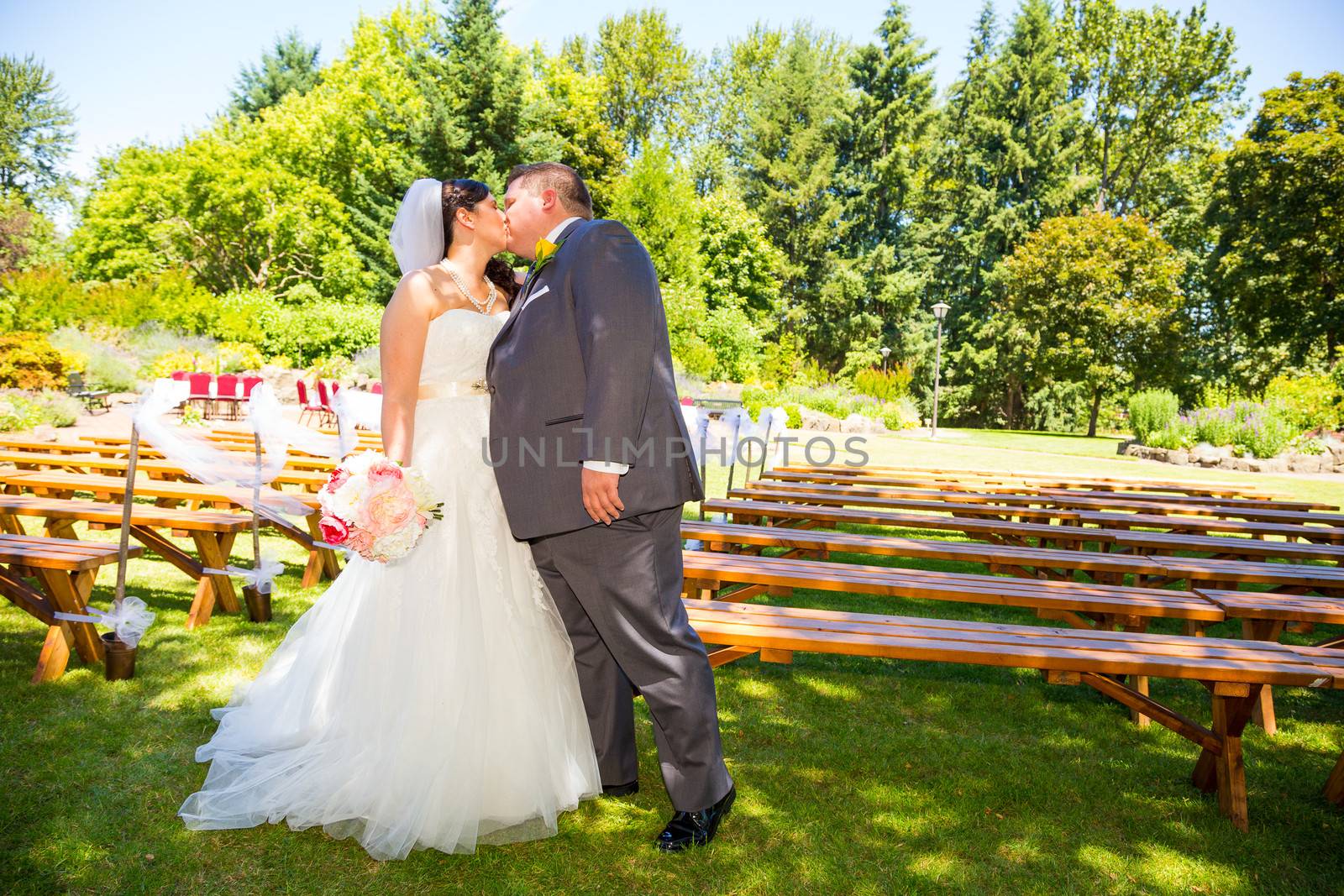 A beautiful bride and groom pose for portraits on their wedding day at a park outdoors.