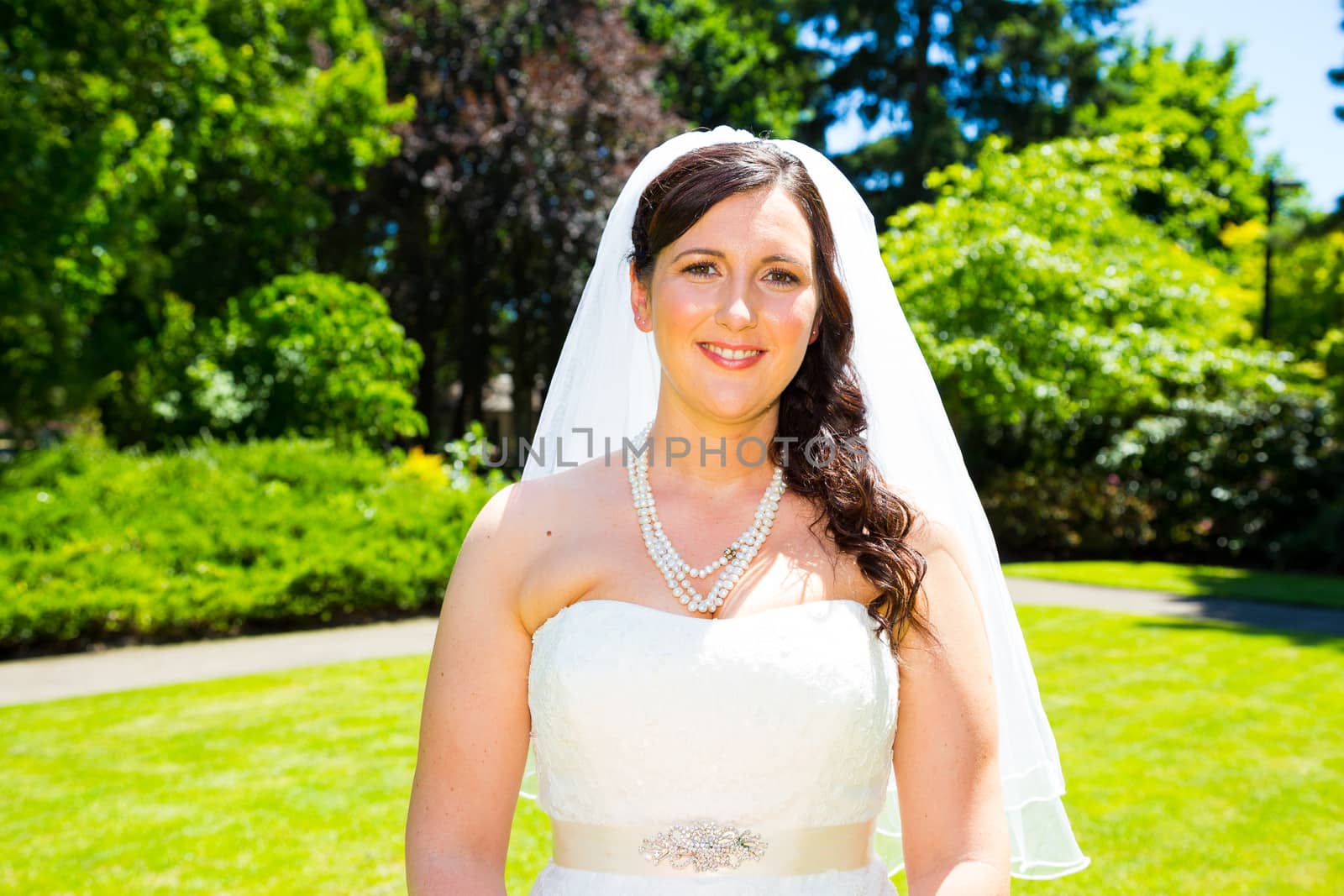 A bride poses for some portraits while wearing her wedding dress at a park outdoors just before here wedding ceremony.