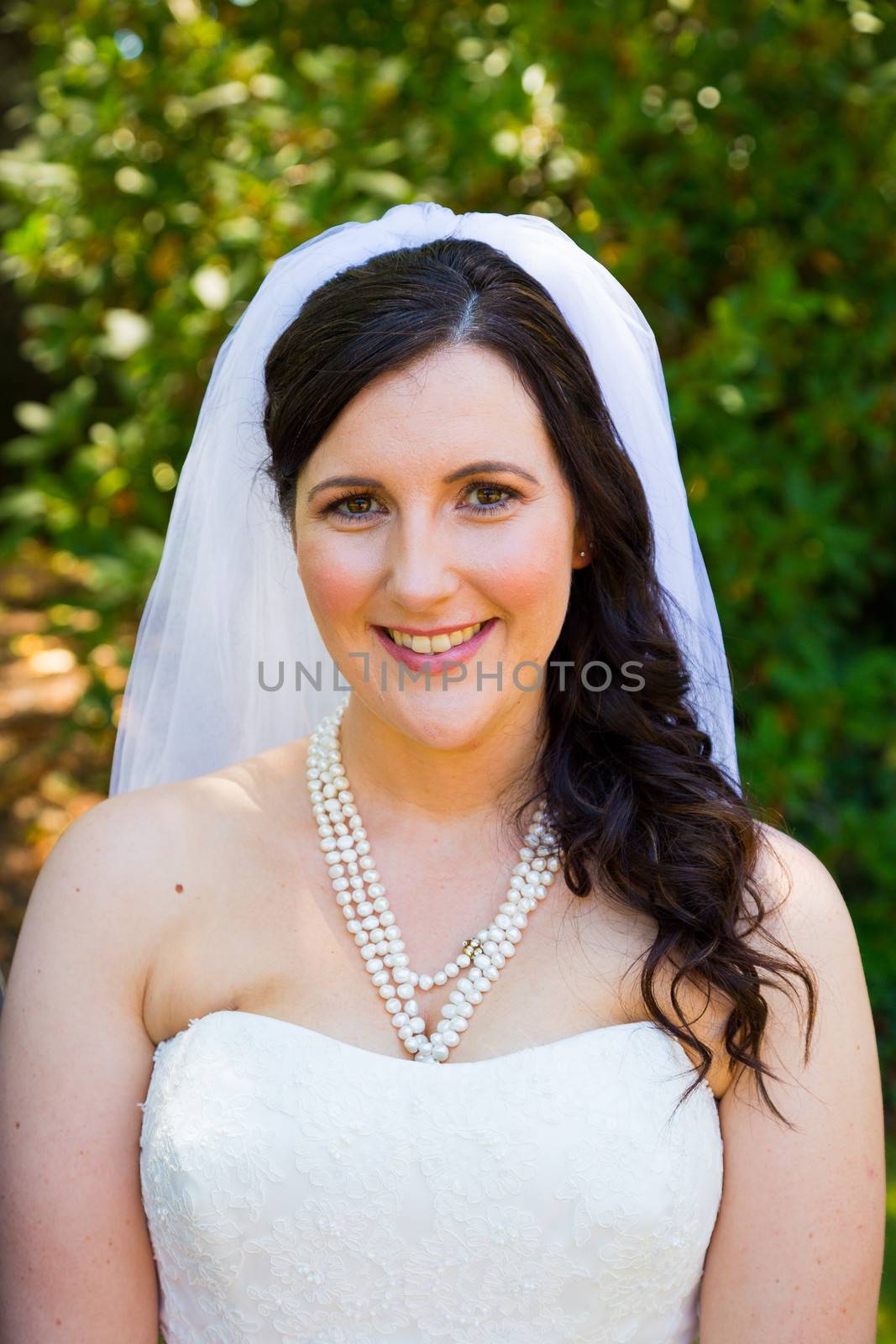 A bride poses for some portraits while wearing her wedding dress at a park outdoors just before here wedding ceremony.