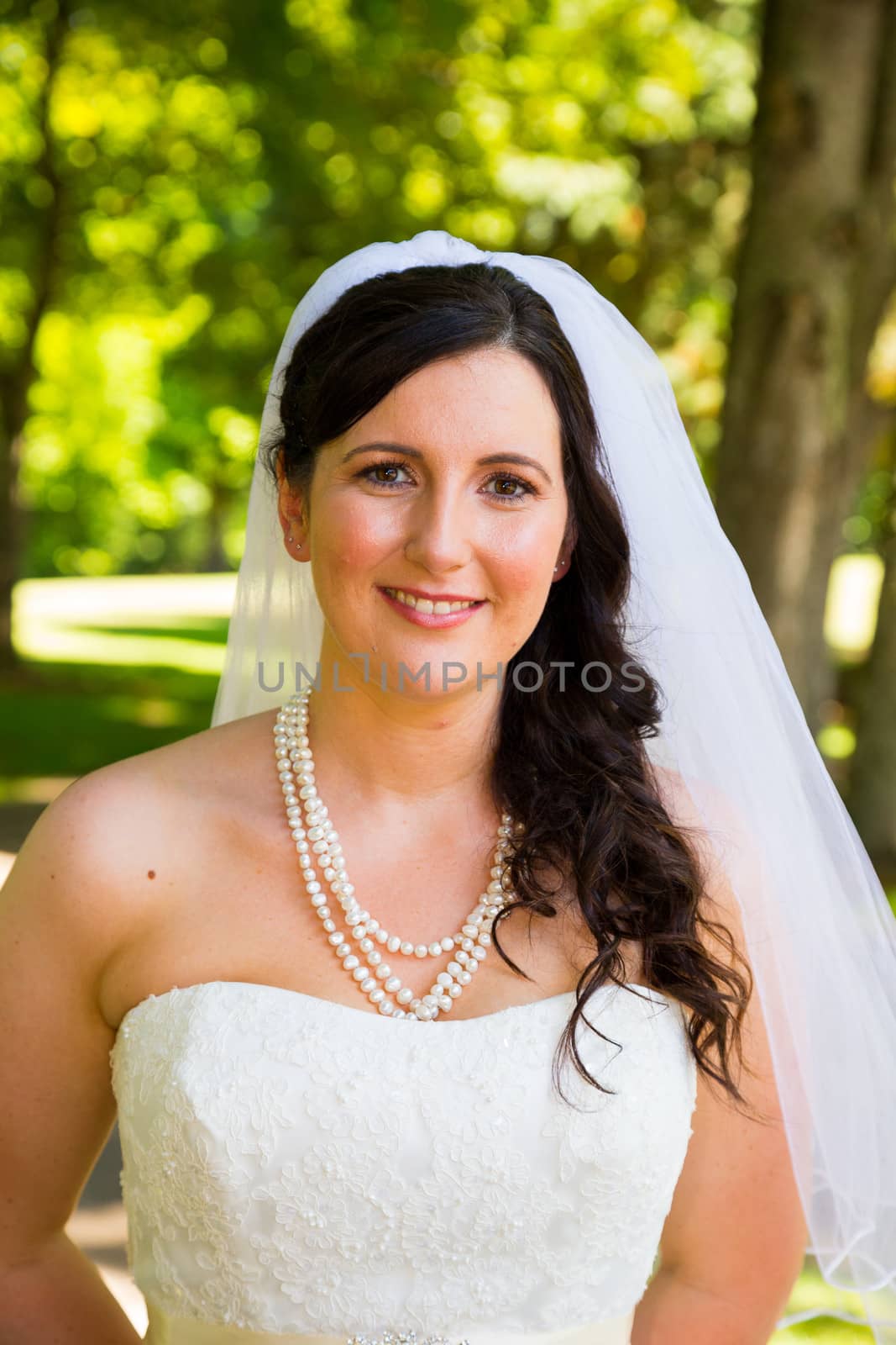 A bride poses for some portraits while wearing her wedding dress at a park outdoors just before here wedding ceremony.