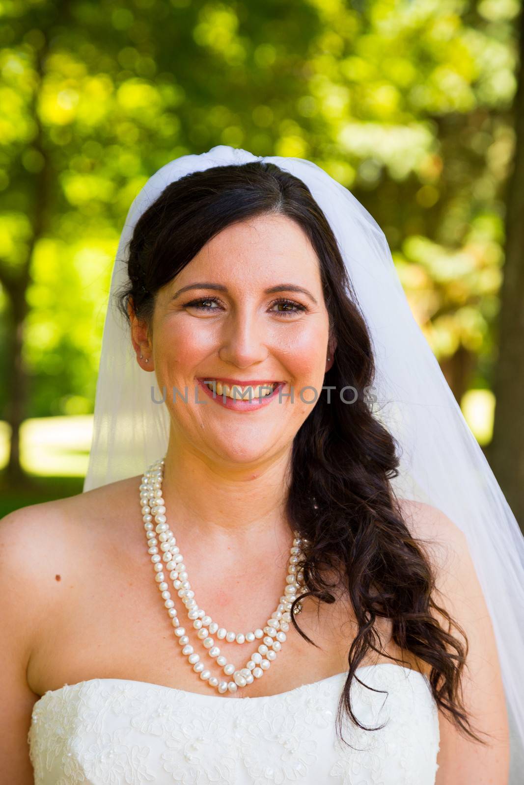 A bride poses for some portraits while wearing her wedding dress at a park outdoors just before here wedding ceremony.