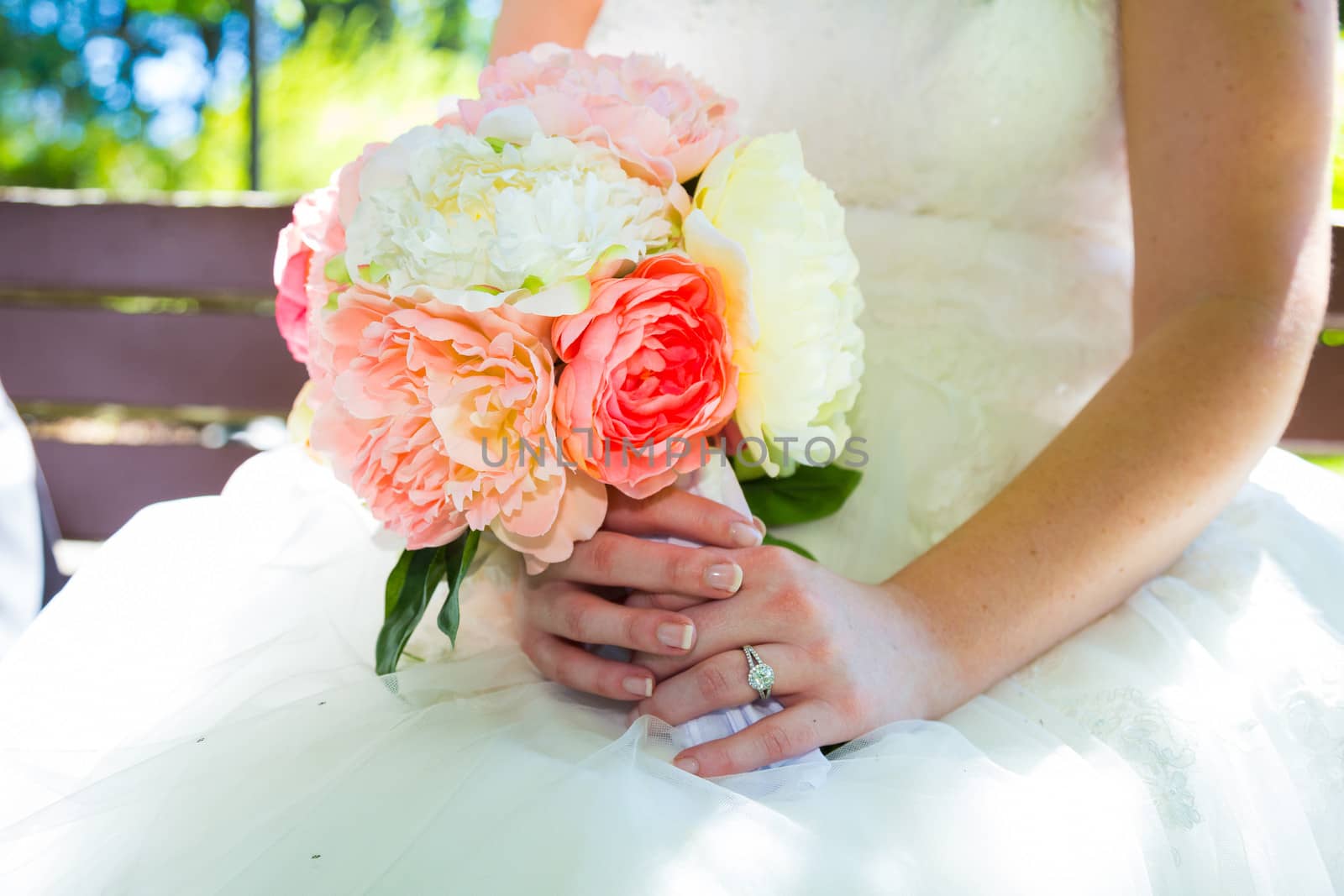This bride holds her bouquet of white and pink flowers against her white wedding dress.