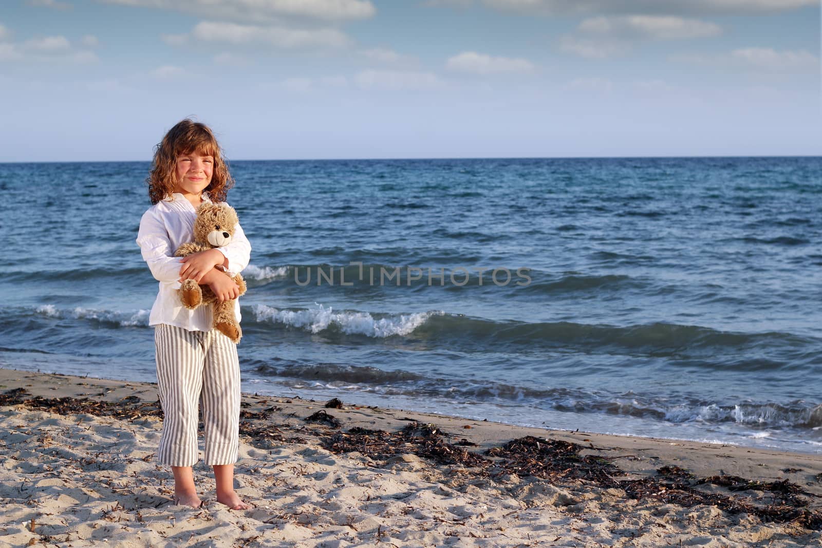 beautiful little girl with teddy bear on beach by goce