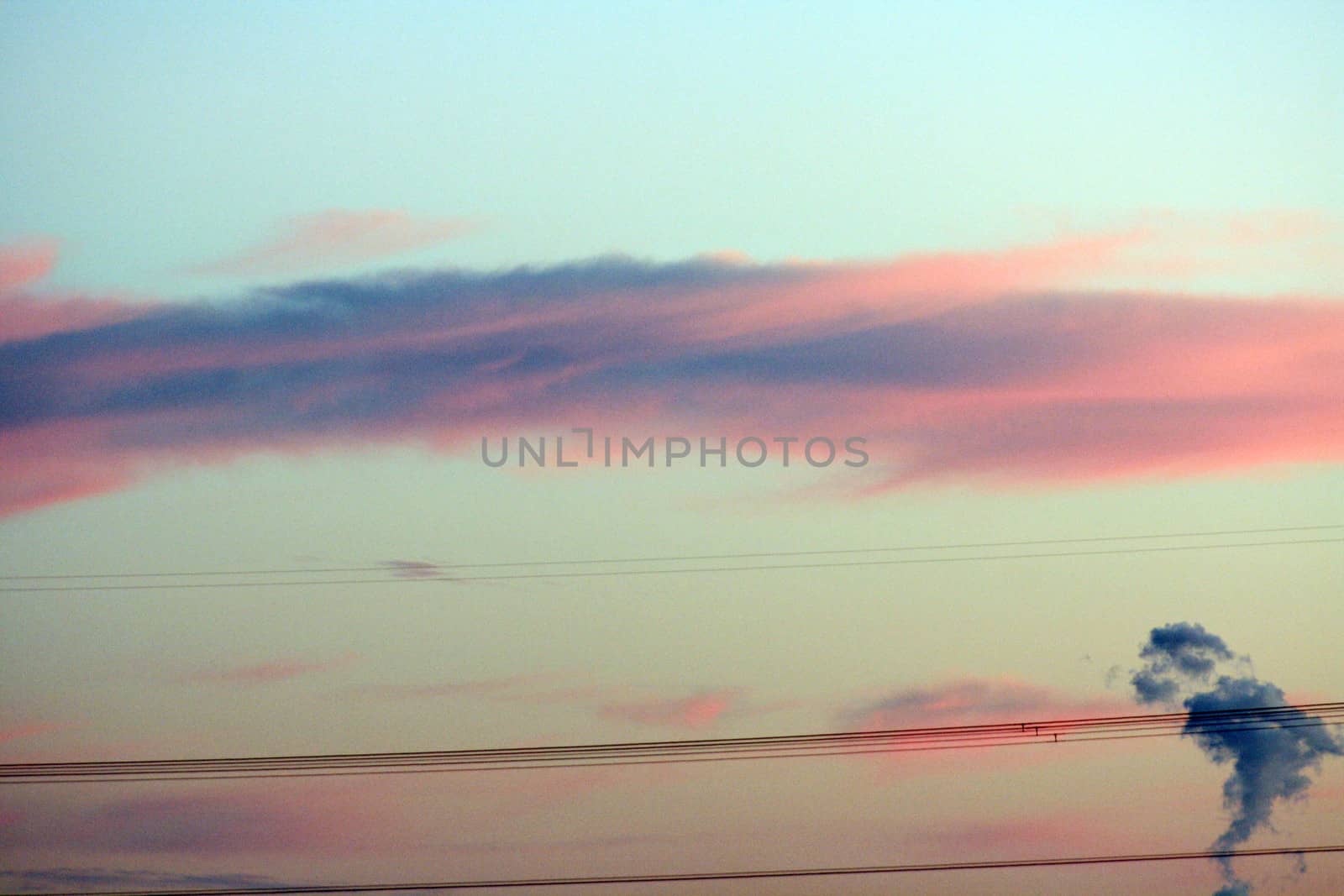 Clouds at sunset through powerline - with small cloud shaped like South America in the lower right corner