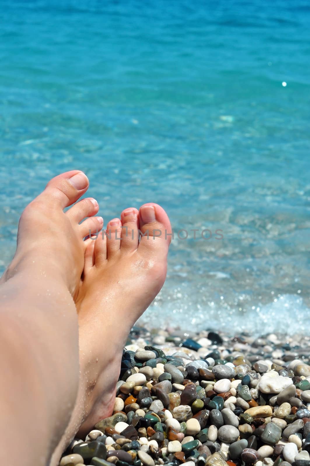 young female feet on the beach with blue water