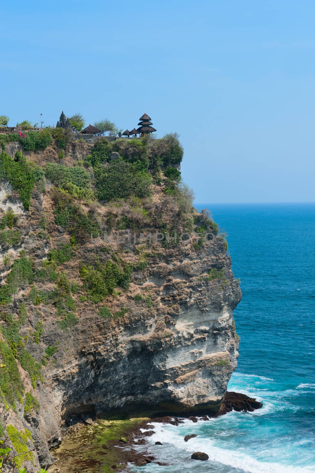 balinese temple on rock above blue tropical sea by iryna_rasko