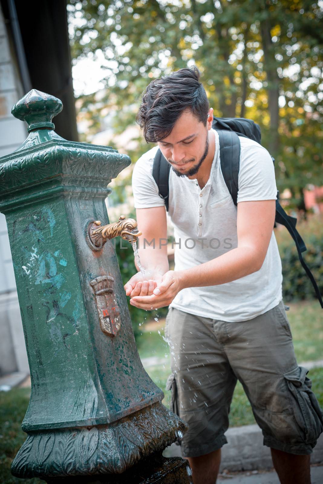 stylish man refreshing at the fountain by peus