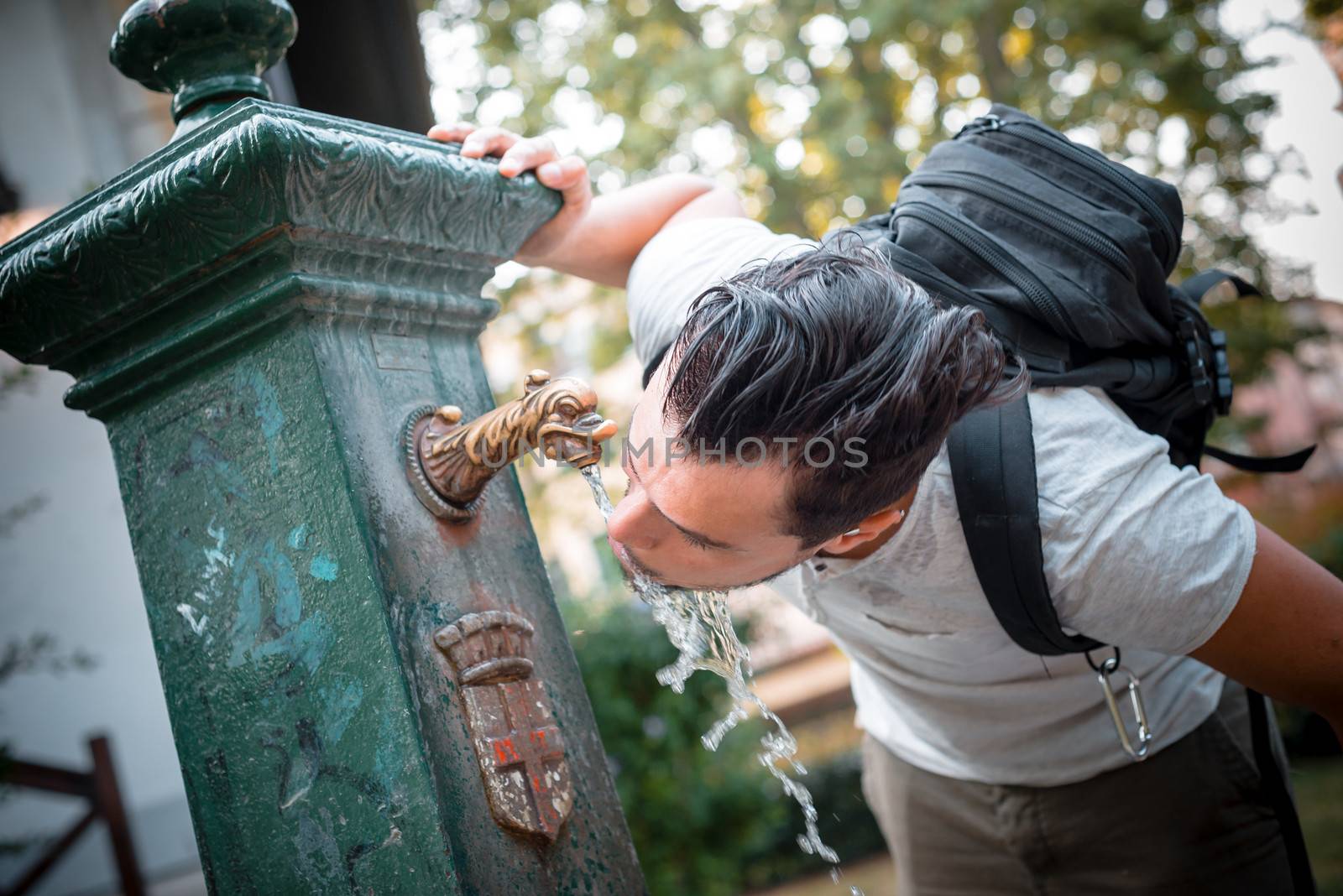 stylish man refreshing at the fountain at the park